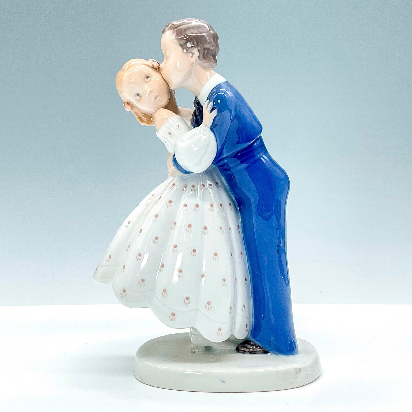 Bing and Grondahl Porcelain Figurine, Youthful Boldness: Glossy pastel piece depicting a boy stealing a kiss from girl #2162. B&G backstamp. Issued: 20th Century Dimensions: 5"L x 3"W x 7"H Manufacturer: Bing & Grondahl Country of Origin: Denmark