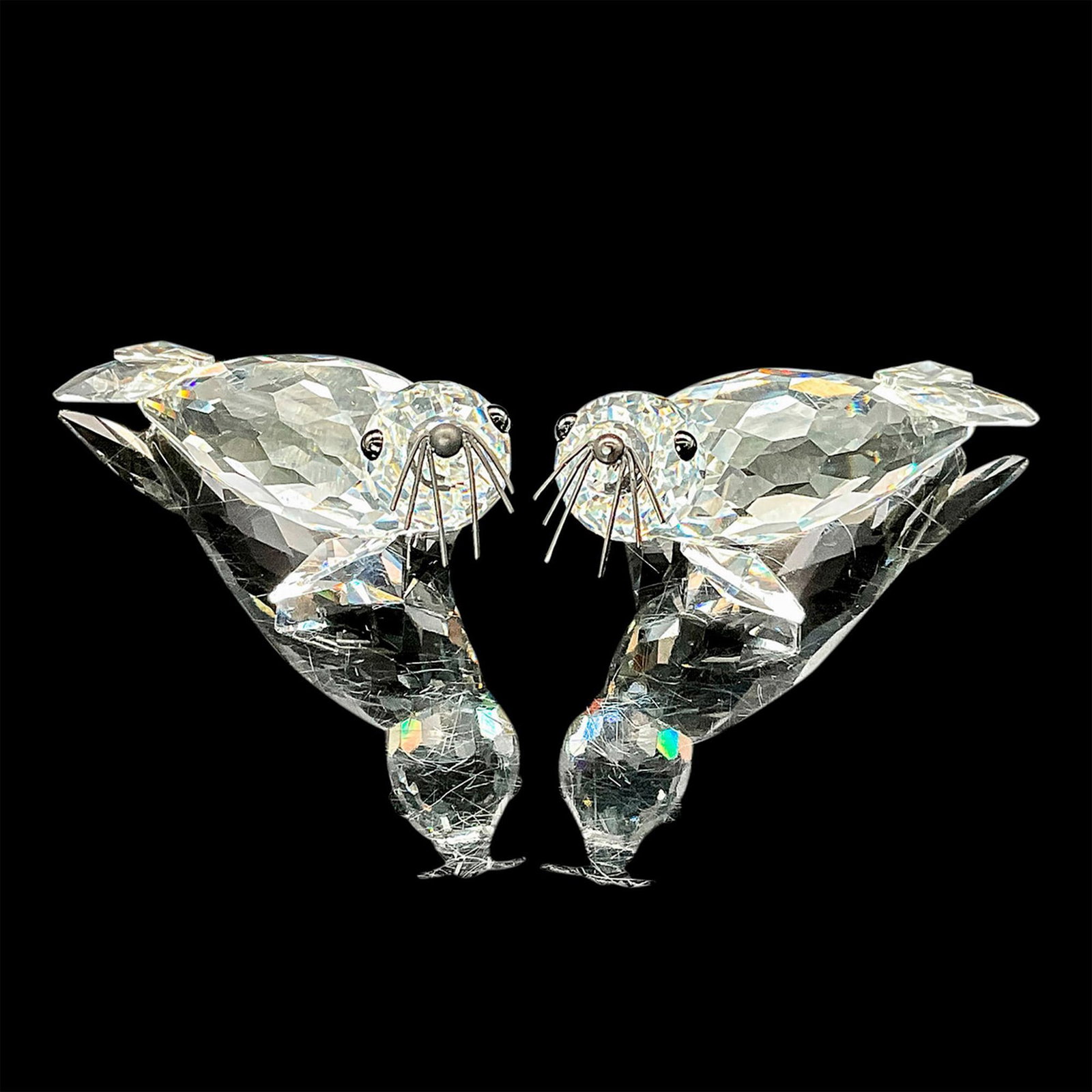 Pair of Swarovski Crystal Figurines, Seals: These adorable seals are constructed in clear faceted crystal with black whiskers and their heads tilted in opposite directions. Swarovski etched backstamp. Largest piece measures 3.75"L x 1.5"W x 1.5