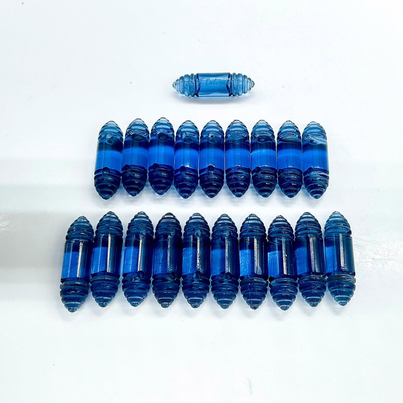 20pc Signed Rene Lalique Glass Bracelet Beads, Renaissance: Loose Renaissance bracelet beads consisting of twenty clear navy blue cylinders with segmented cone ends designed by Rene Lalique in 1928. One bead signed R. Lalique. Rene Lalique was a master glass m