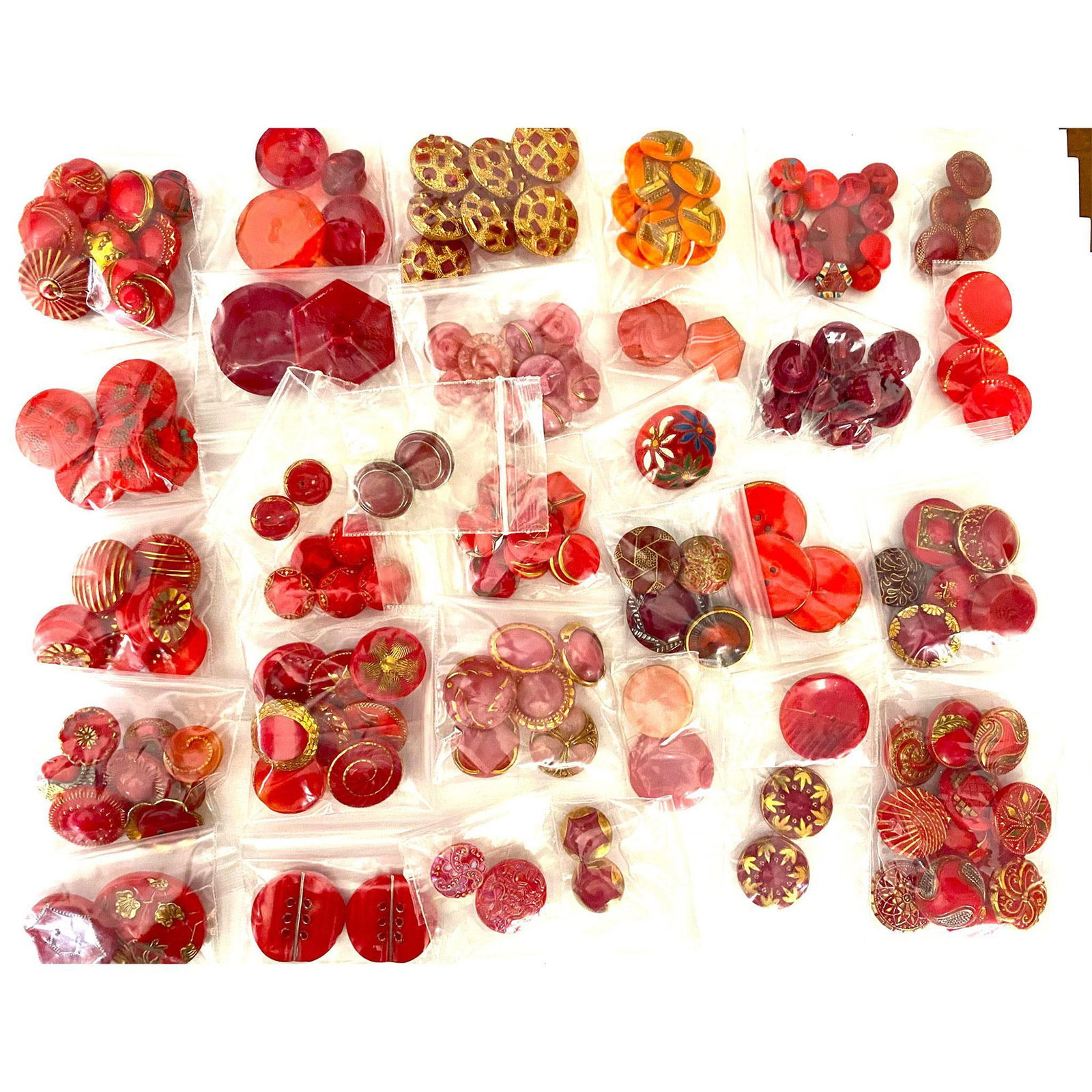 A Large Bag Lot of Buttons: A variety of assorted red and red shades of glass buttons. These bag lots and the next one came to us from a consignor that had already bagged the buttons in sets and look a-likes, so we have left the
