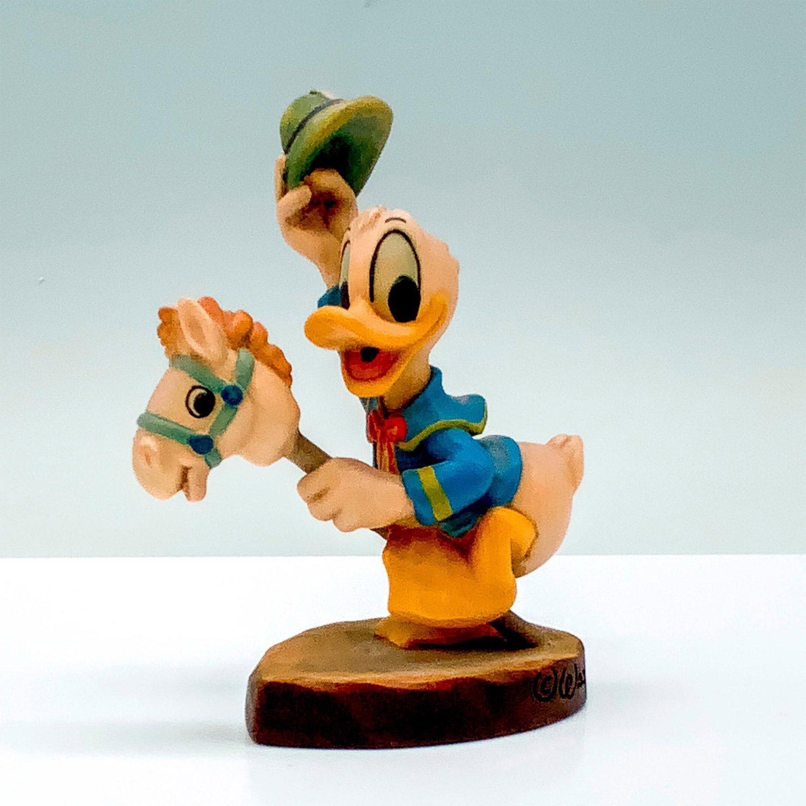 Anri Walt Disney Rider Donald Figurine: A carved wooden figure of Donald Duck in his classic outfit holding a safari hat while riding his hobby horse. Anri backstamp. Walt Disney Company backstamp. Dimensions: 3"L x 1.5"W x 4"H Edition Numb
