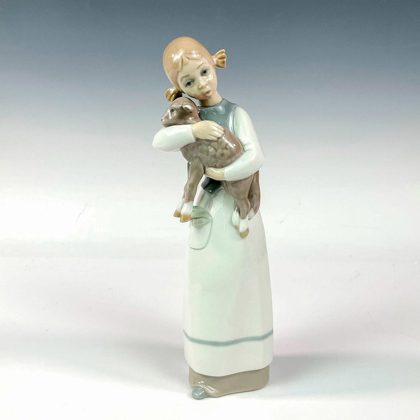 Girl With Lamb 1001010 - Lladro Porcelain Figurine: Glossy finish; Lladro backstamp. Artist: Julio Fernandez Issued: 1969 - 1993 Dimensions: 8.75"H x 3.25"W Manufacturer: Lladro Country of Origin: Spain
