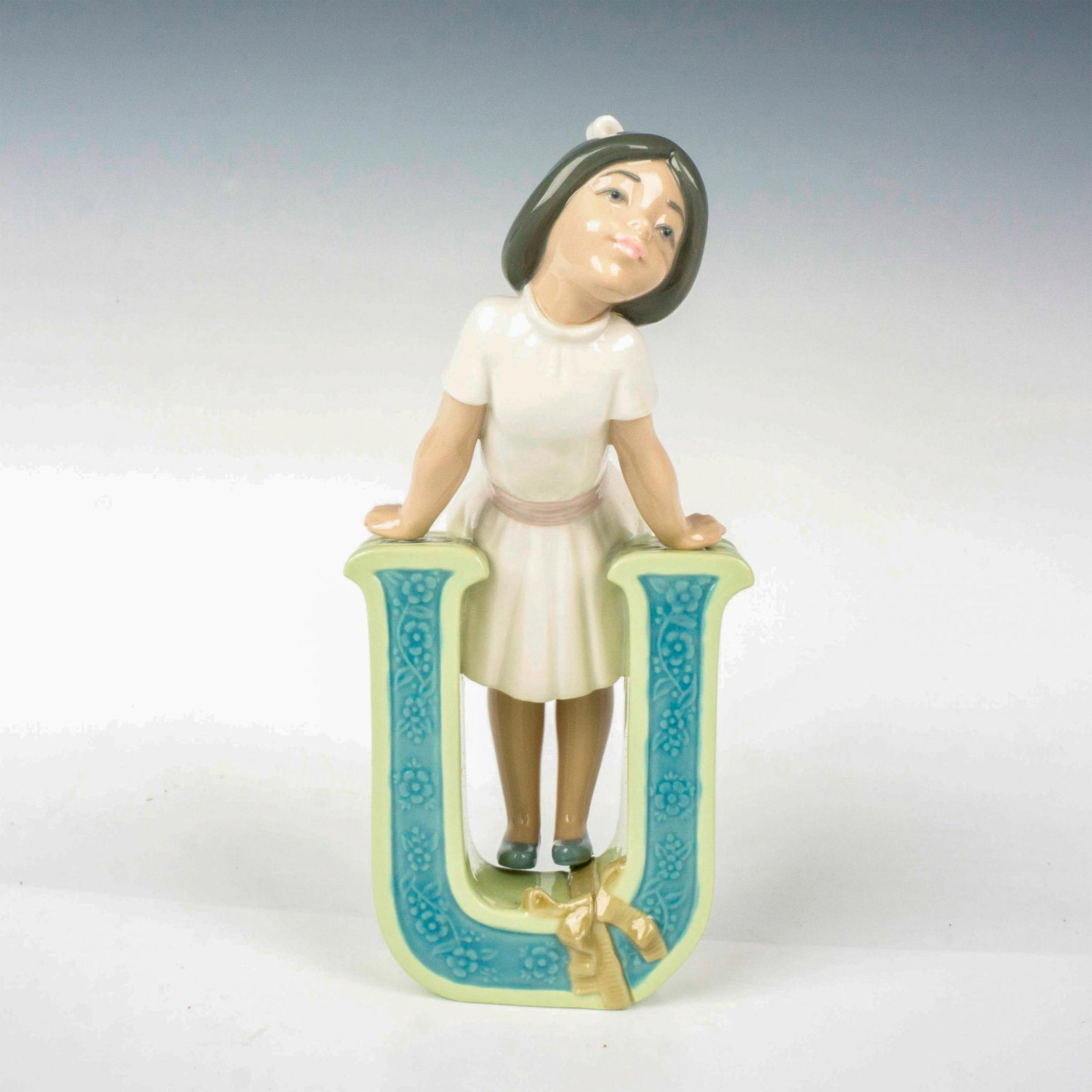 Schoolgirl U 1005149 - Lladro Porcelain Figurine: Glossy finish; Lladro backstamp. Includes original box. Box measures: 10.75"L x 5.5"W x 5"H. Artist: Jose Puche Issued: 1982 - 1985 Dimensions: 7.75"H Manufacturer: Lladro Country of Origin: Spain