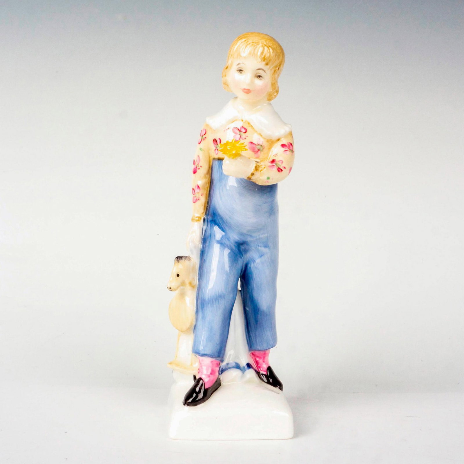 Tom - HN2864 - Royal Doulton Figurine: Bone china figure of a child with toy horse and flower in hands. Royal Doulton backstamp. Artist: Peggy Davies Issued: 1978 - 1981 Dimensions: 5.75"H Manufacturer: Royal Doulton Country of Origin: