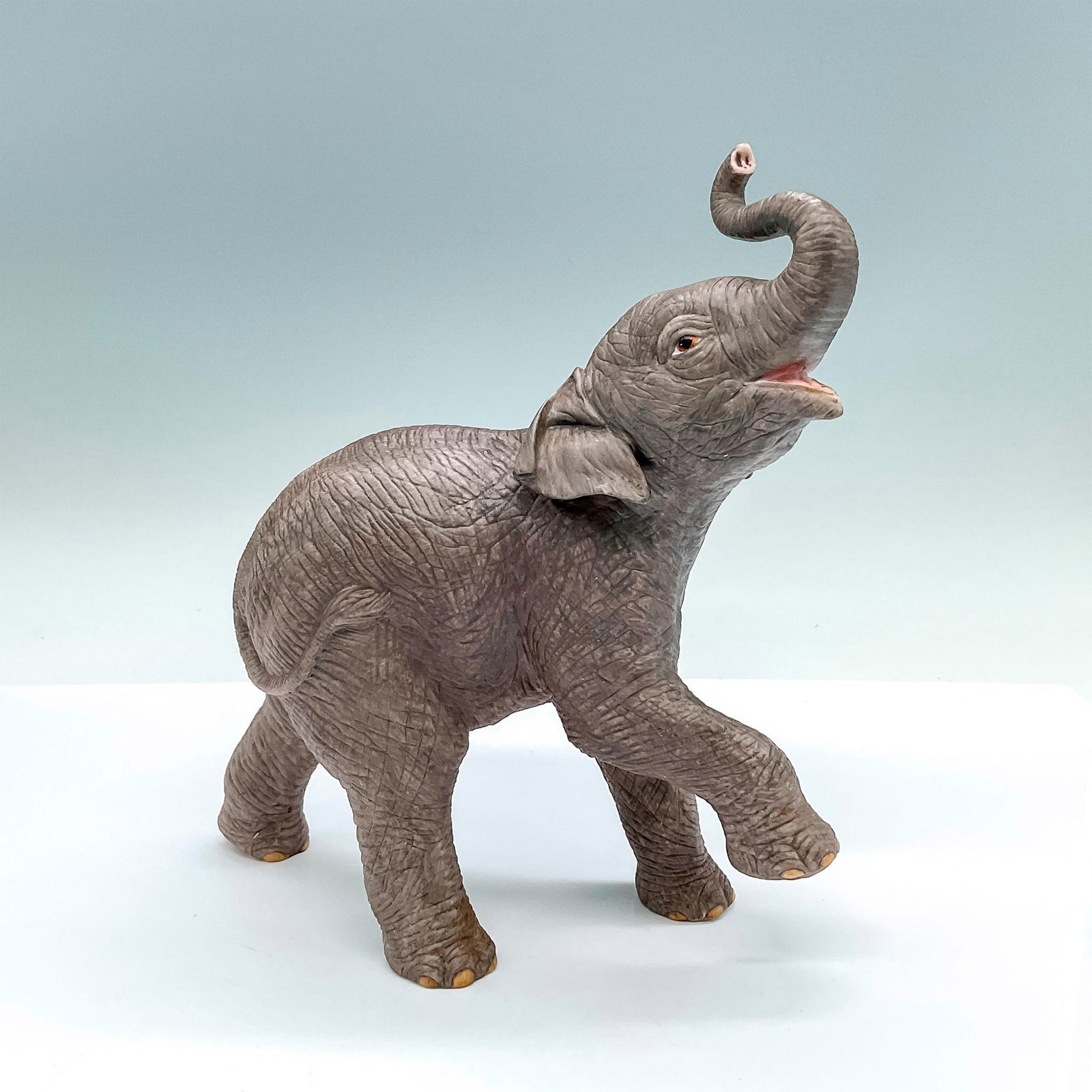 Lenox Fine Porcelain Figurine, Asian Elephant: Part of the Smithsonian Institution collection; a naturalistic matte finish figure of an elephant with its trunk in the air. Lenox backstamp. Issued: 1992 Dimensions: 7"L x 3.25"W x 8.25"H Manufacture