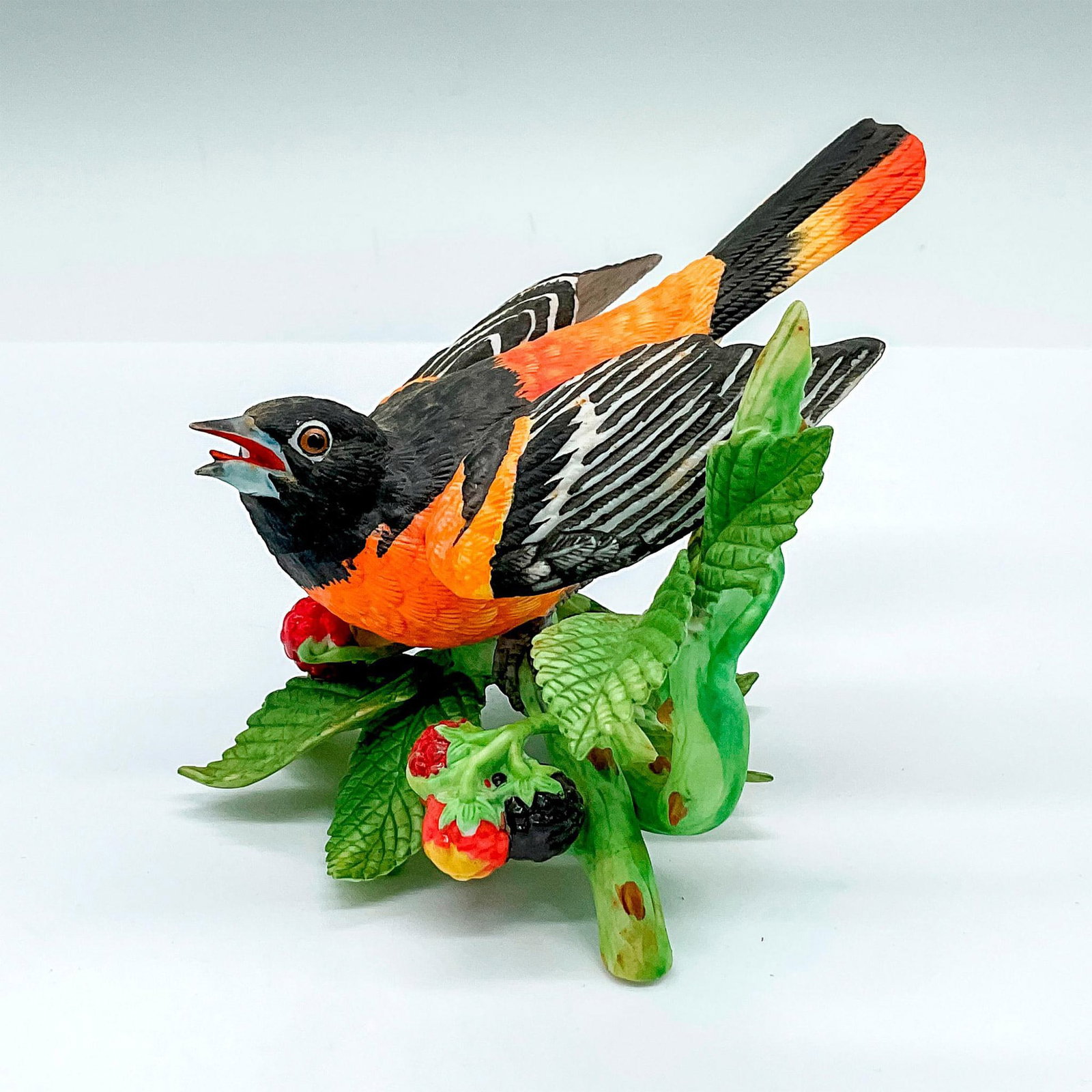 Lenox Fine Porcelain Figurine, Baltimore Oriole: A beautiful orange and black bird perched on a red raspberry branch. Lenox backstamp. Issued: 1990 Dimensions: 4.5"L x 4.5"W x 3.5"H Manufacturer: Lenox