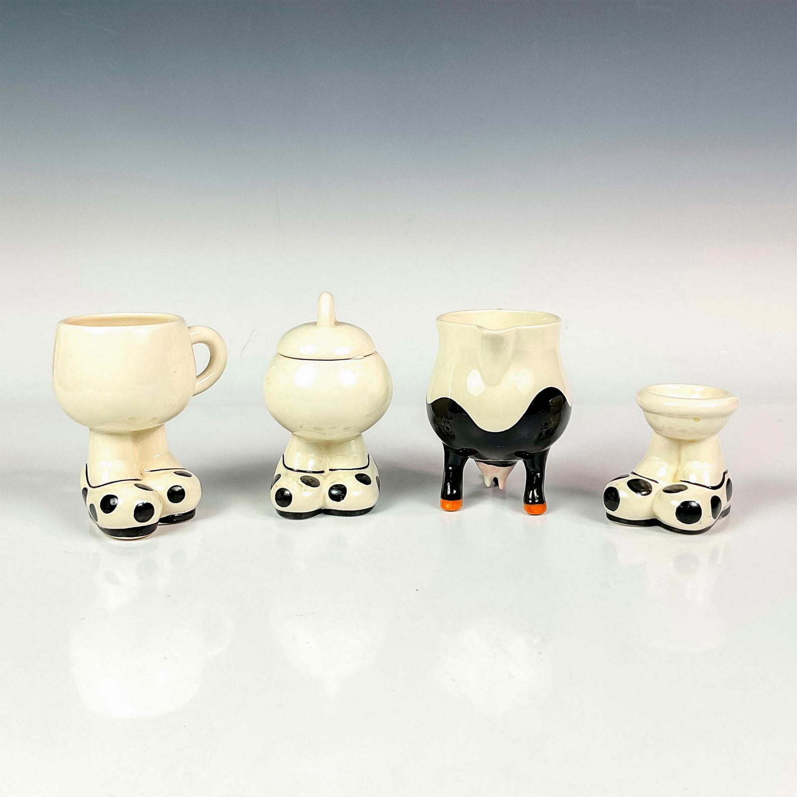 4pc Carlton Ware Breakfast Service Set: Includes a ceramic footed character egg cup, coffee cup, sugar bowl and creamer. Each item is designed with comical oversized feet in poke a dot slippers. Sugar bowl has a lid. Also includes figural c