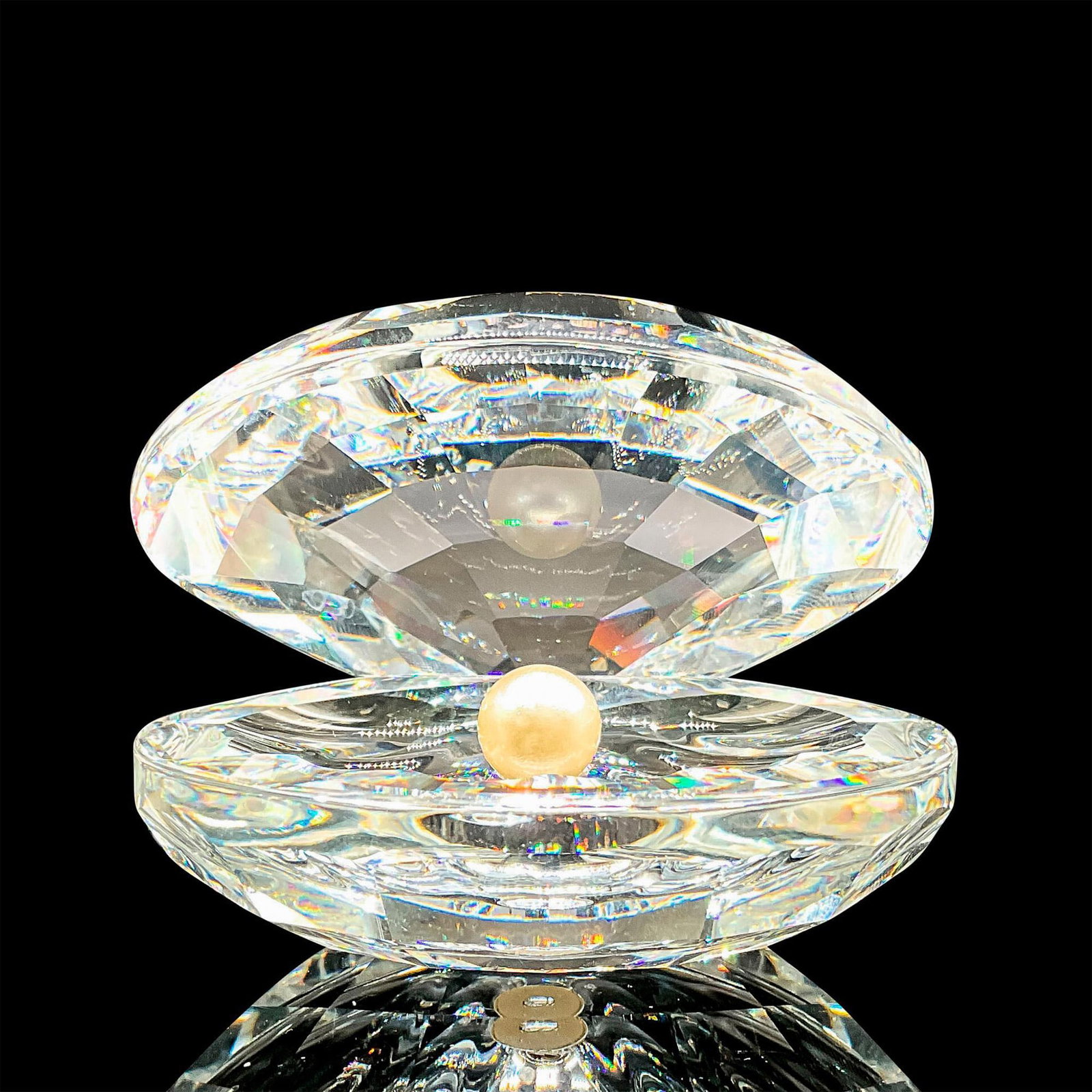 Shell with Pearl - Swarovski Crystal Figurine: Part of the Aquatic Worlds theme group. A faceted clear open clam shell with a white crystal pearl inside. Swarovski laser etched marking on the base. Artist: Michael Stamey Issued: c. 1988-2017 Dimen