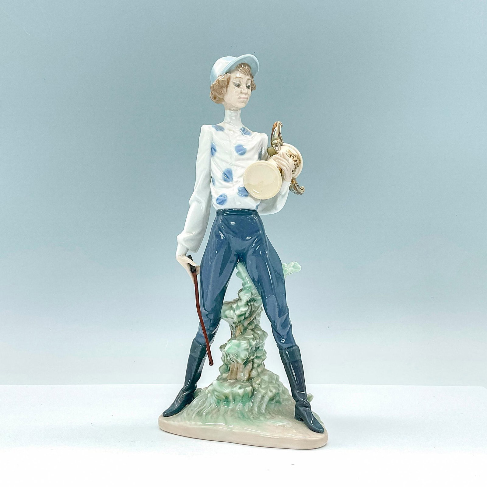 Lladro Prototype Figurine, Jockey Uncatalogued PP138: Beautiful glossy porcelain depiction of a jockey holding a trophy. Lladro backstamp. Dimensions: 4.75"L x 3.25"W x 10"H Manufacturer: Lladro Country of Origin: Spain