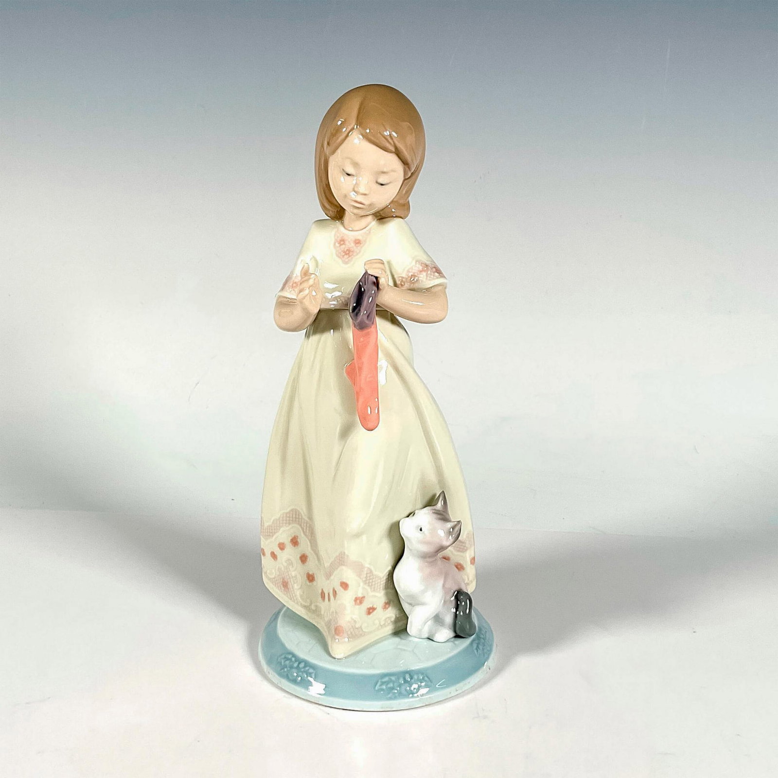 A Stocking For Kitty 1006669 - Lladro Porcelain Figurine: Glossy finish; Lladro backstamp. Includes original box. Box measures: 5.5"L x 11"W x 5"H. Artist: Joan Coderch Issued: 1999 - 2001 Dimensions: 8.5"H Manufacturer: Lladro Country of Origin: Spain