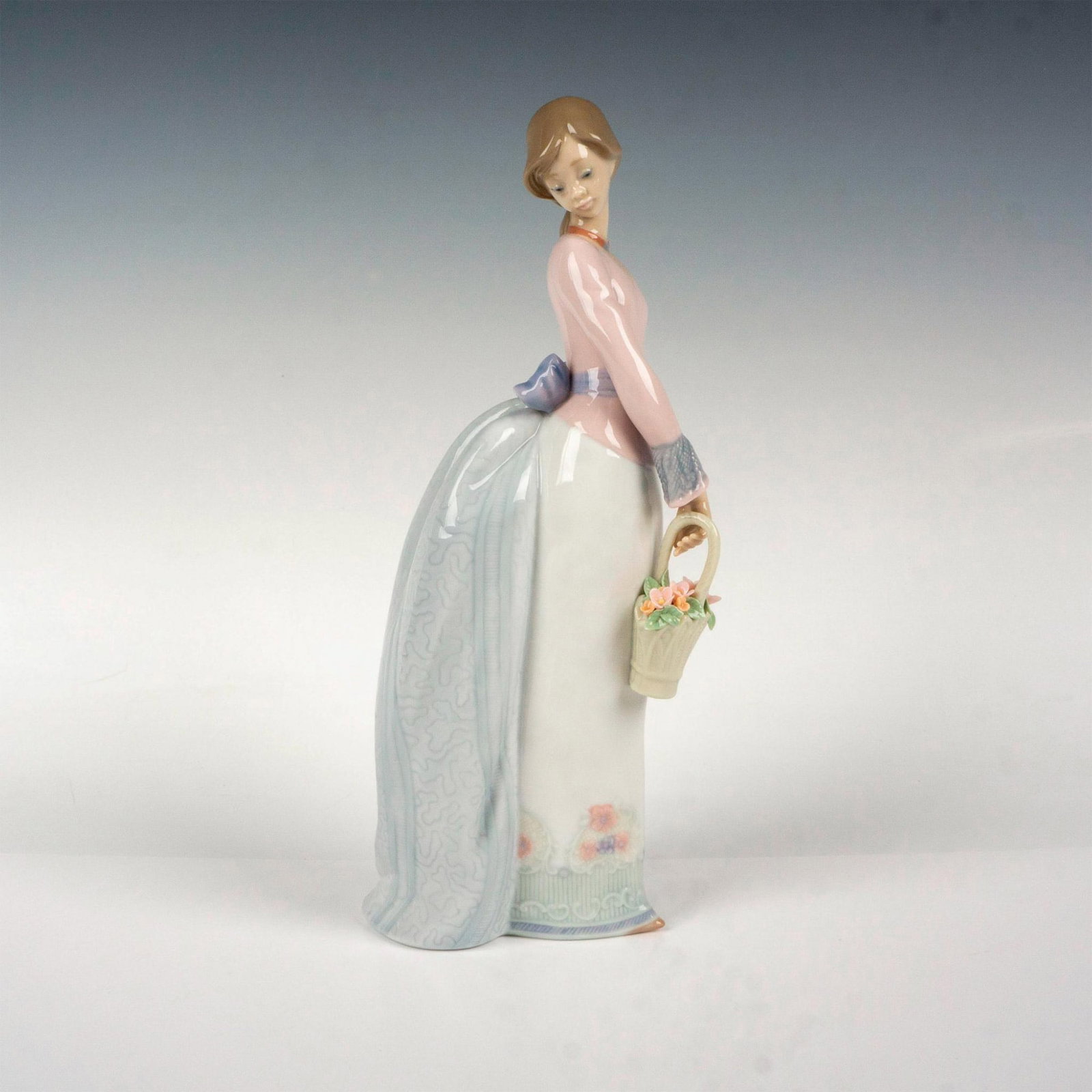 Basket Of Love 1007622 - Lladro Porcelain Figurine: Glossy finish; Lladro backstamp. Artist: Jose Puche Issued: 1994 - 1994 Dimensions: 9.75"H x 4"W Manufacturer: Lladro Country of Origin: Spain