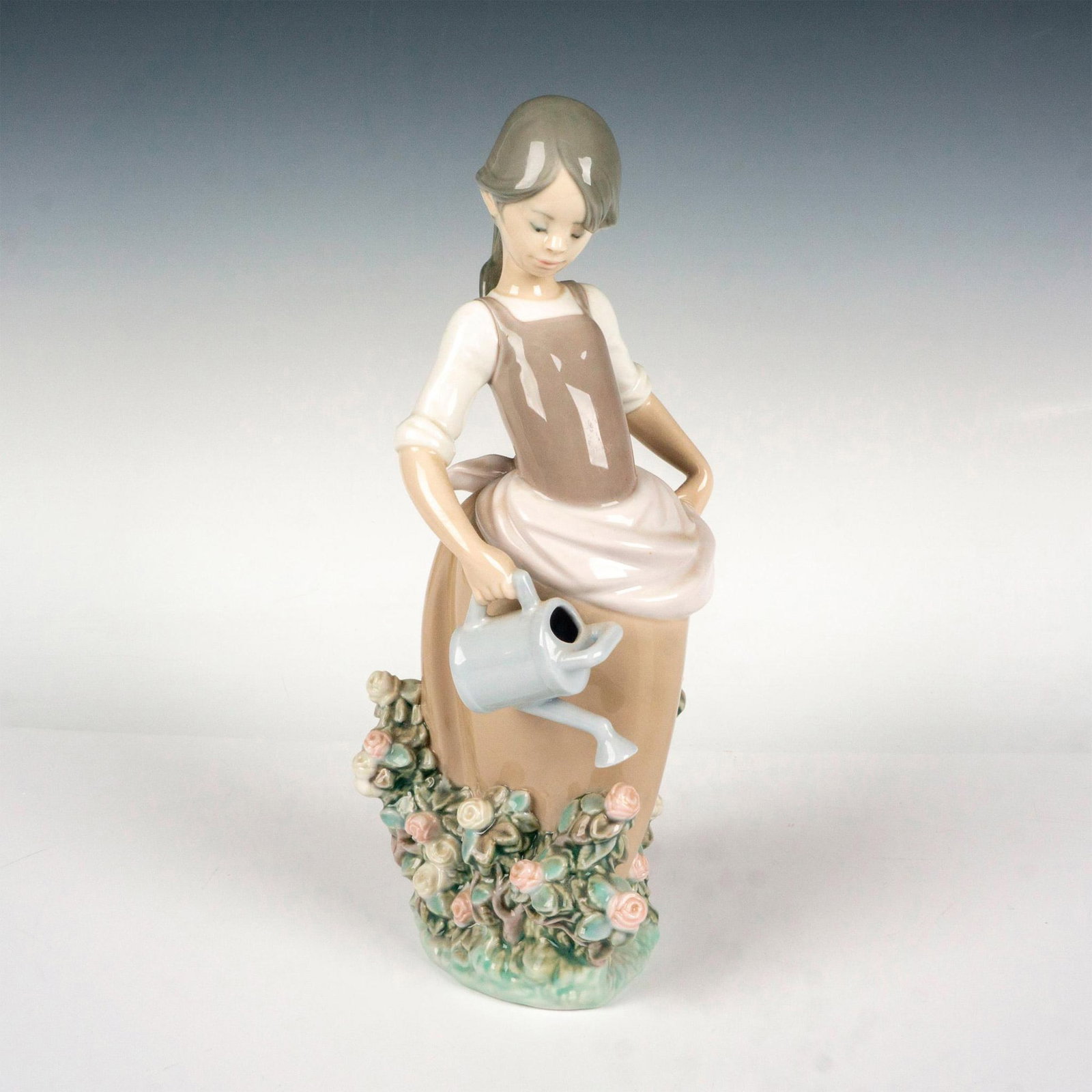 Girl With Watering Can 1001339 - Lladro Porcelain Figurine: Glossy finish; Lladro backstamp. Artist: Juan Huerta Issued: 1977 - 1988 Dimensions: 11.5"H Manufacturer: Lladro Country of Origin: Spain