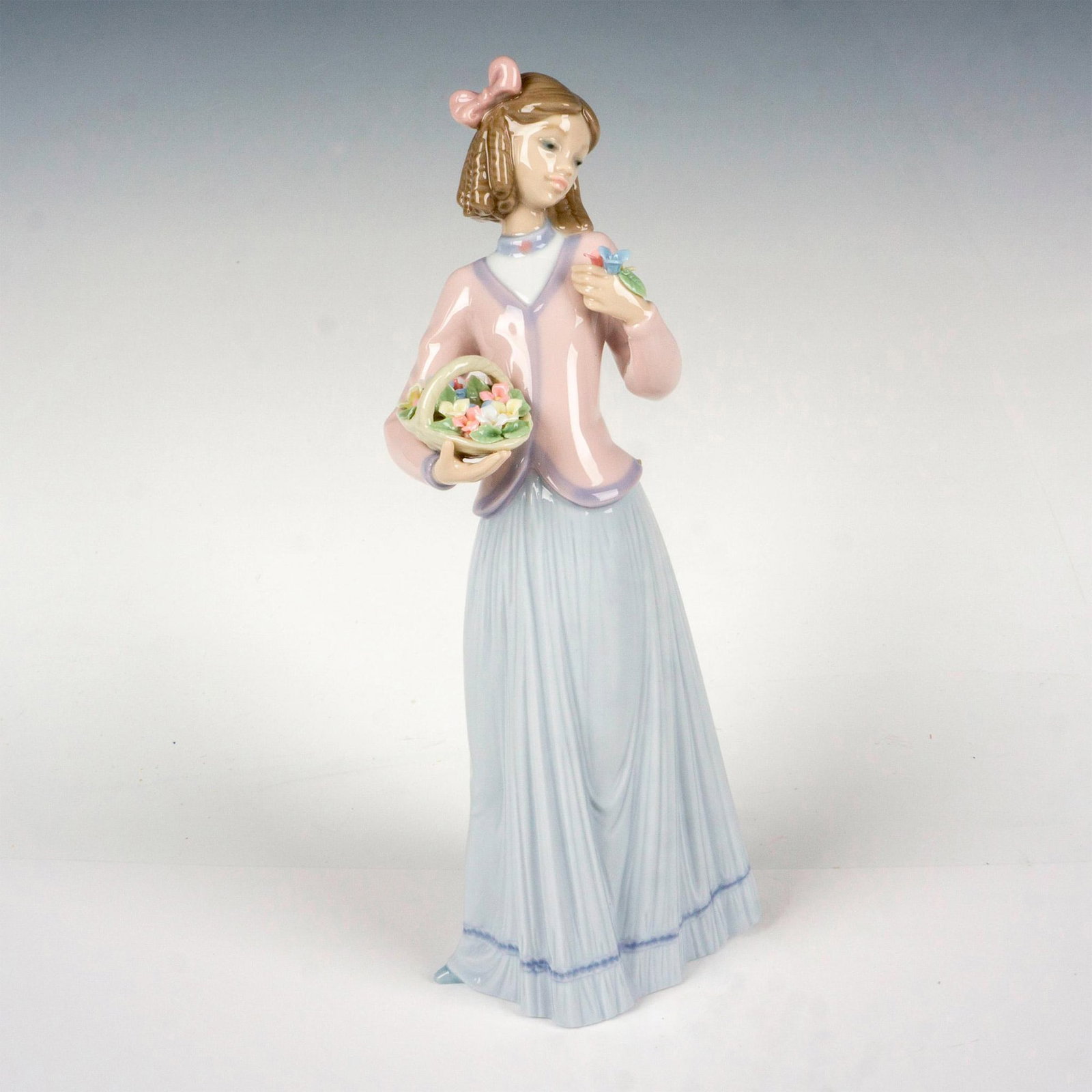 Innocence In Bloom 1007644 - Lladro Porcelain Figurine: Glossy finish; Lladro backstamp. Artist: Jose Puche Issued: 1996 - 1996 Dimensions: 9.75"H x 4.25"W Manufacturer: Lladro Country of Origin: Spain