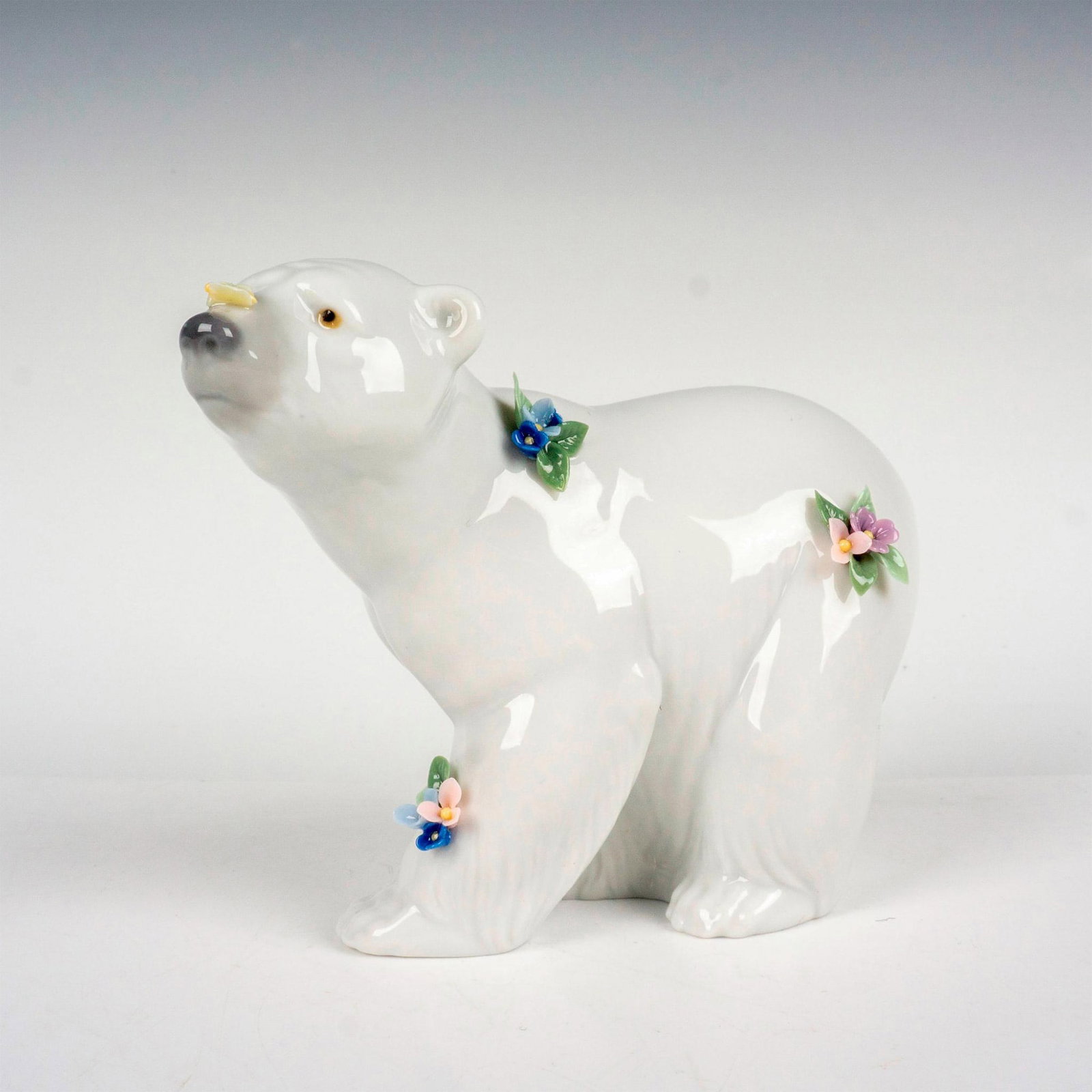 Attentive Polar Bear With Flowers 1006354 - Lladro Porcelain Figurine: Glossy finish porcelain; Intricate floral detailing. Lladro backstamp. Artist: Juan Huerta Issued: 1997-2004 Dimensions: 2"L x 5"W x 4"H Manufacturer: Lladro Country of Origin: Spain