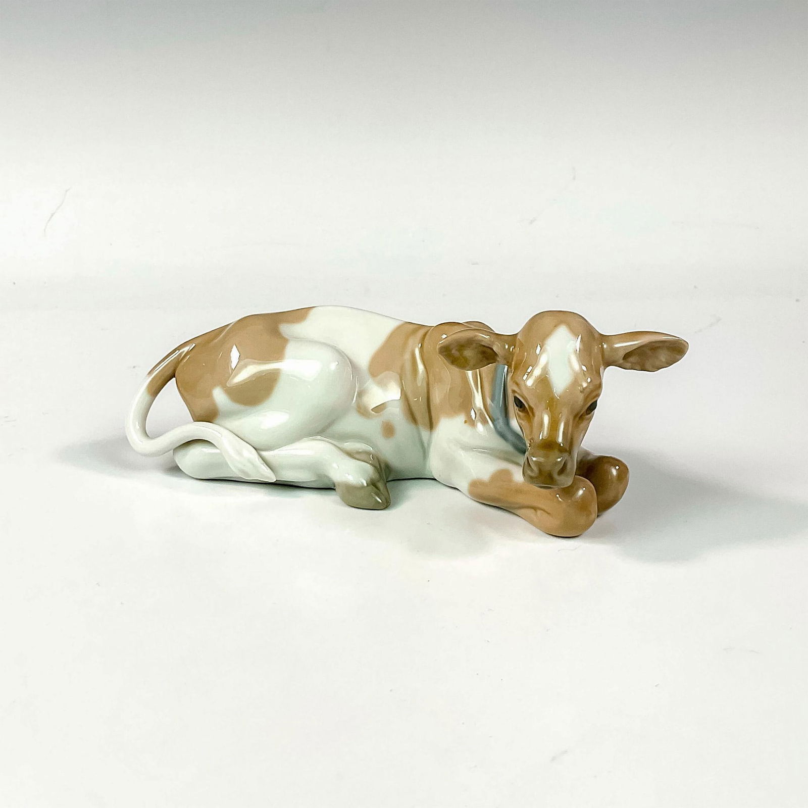 Cow 1004680 - Lladro Porcelain Figurine: Glossy finish; Lladro backstamp. Artist: Juan Huerta Issued: 1969 - 2001 Dimensions: 2.25"H Manufacturer: Lladro Country of Origin: Spain