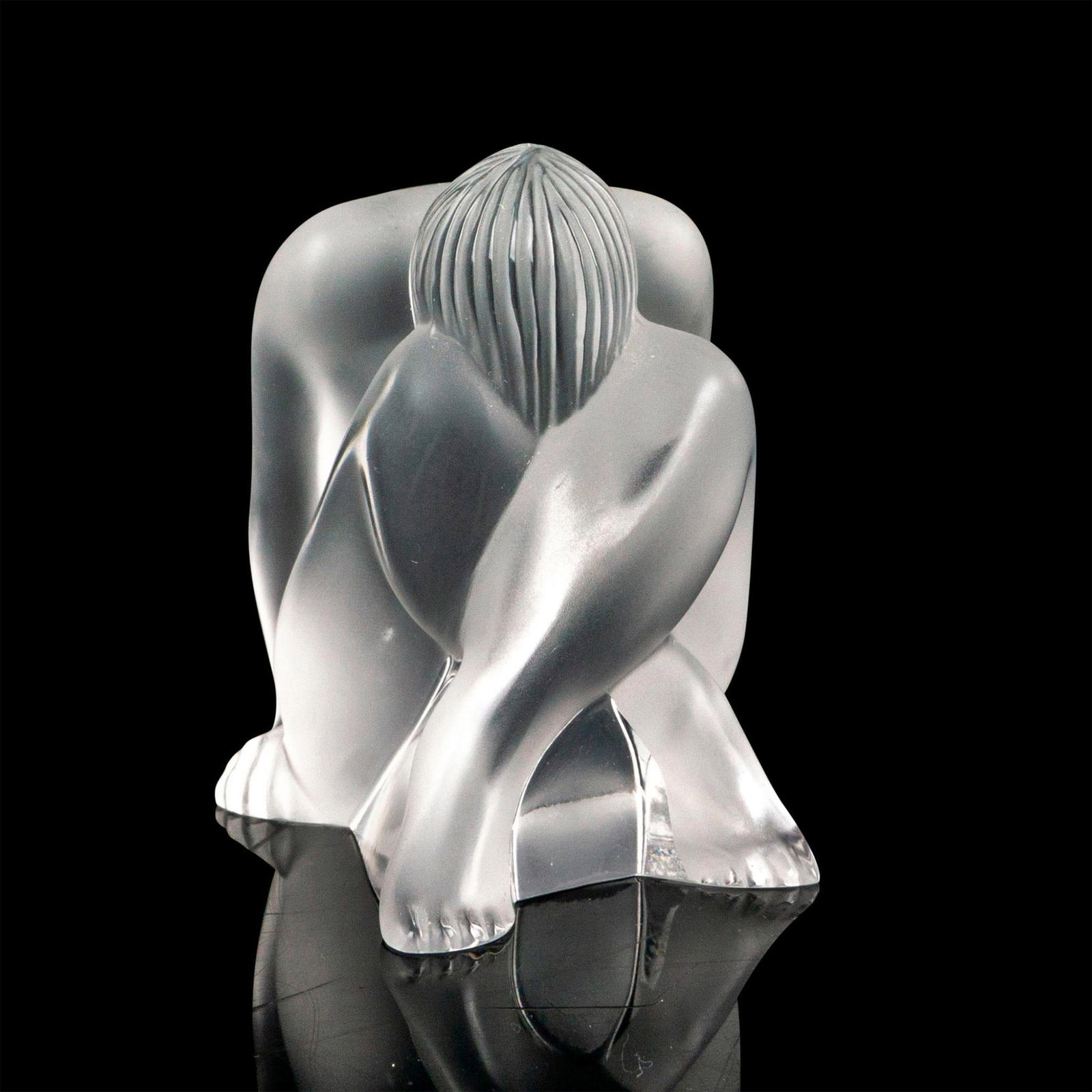 Lalique Crystal Nude Figurine, Nu Reve Seated: Figure of a person at rest with their face tucked into their knees. Nude series of a body in various static poses. Satin finish piece. Etched Lalique France at the bottom. Dimensions: 2"L x 2"W x 2.5"