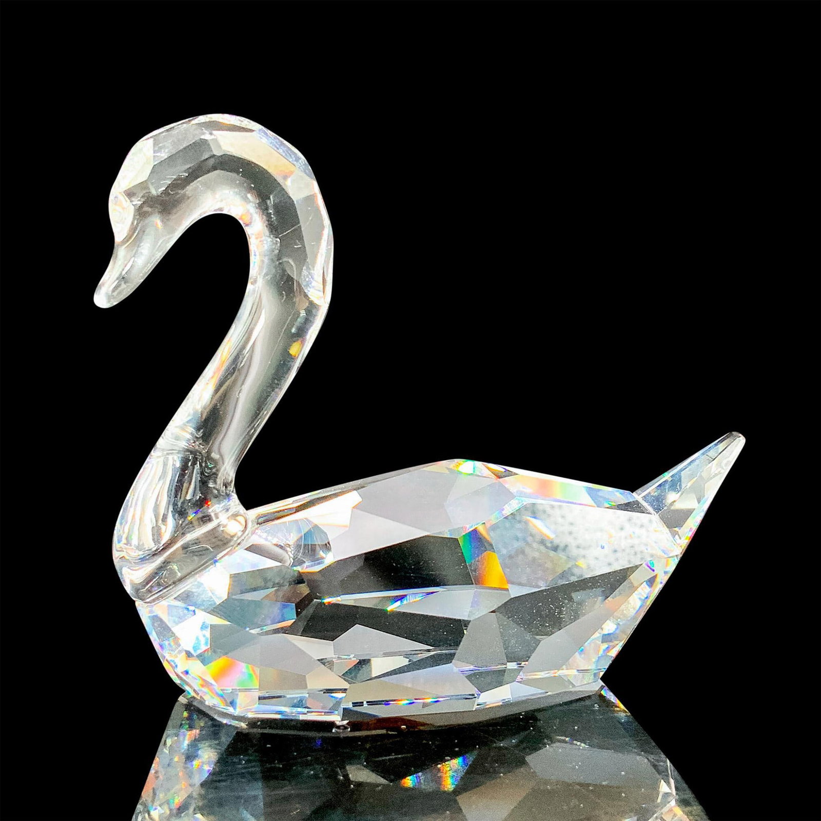 Swarovski Crystal Figurine, Swan 844168: A pure clear crystal swan with different cuts throughout the body in a seated position with the tail pointed out. Swarovski backstamp. This item has its original box. Dimensions of the original box: 5