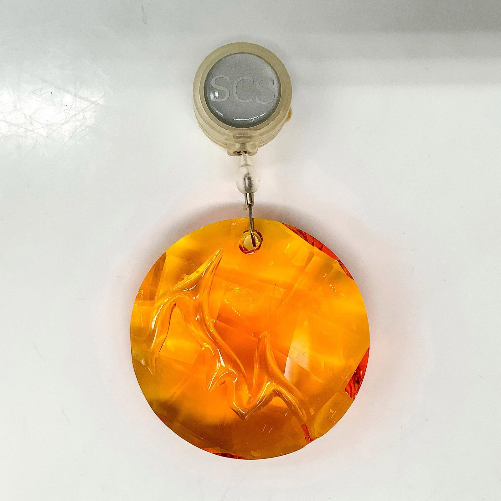 Swarovski Crystal Fire Ornament 1017151: An orange-colored round crystal ornament with a flame symbol carved into the center. Swarovski backstamp. This item has its original box. Dimensions of the original box: 3.75"L x 3.75"W x 1.25"H. Arti