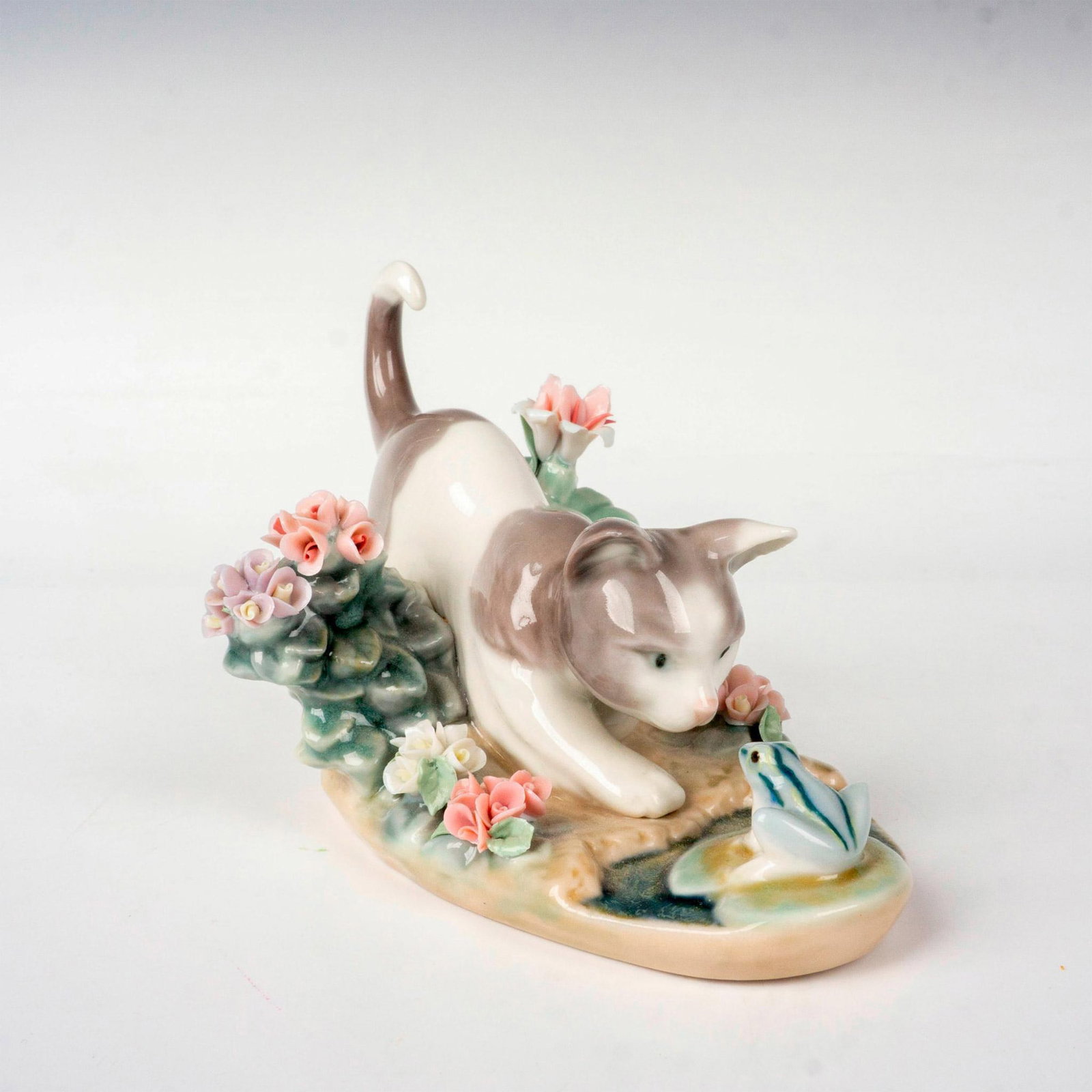Kitty Confrontation 1001442 - Lladro Porcelain Figurine: Glossy finish, modeled as a kitten playing with a frog. Lladro backstamp. Artist: Juan Huerta Issued: 1983-2023 Dimensions: 2.75"L x 4.75"W x 3.5"H Manufacturer: Lladro Country of Origin: Spain