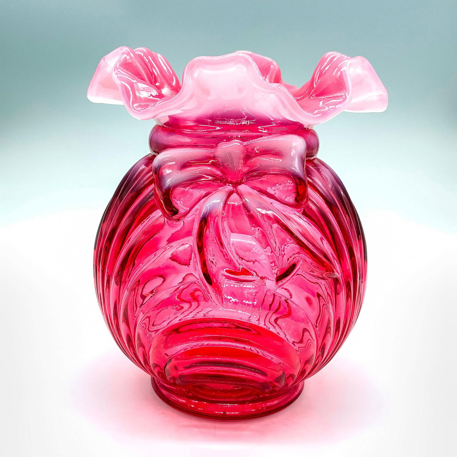 Fenton Art Glass Country Cranberry Caprice Vase With Bow: Beautiful vase with embossed ridges in cranberry color with unique white frosting on the ruffled rim and bow. Fenton stamp on the bottom. Dimensions: 5.25"dia. x 6.25"H Manufacturer: Fenton Country of