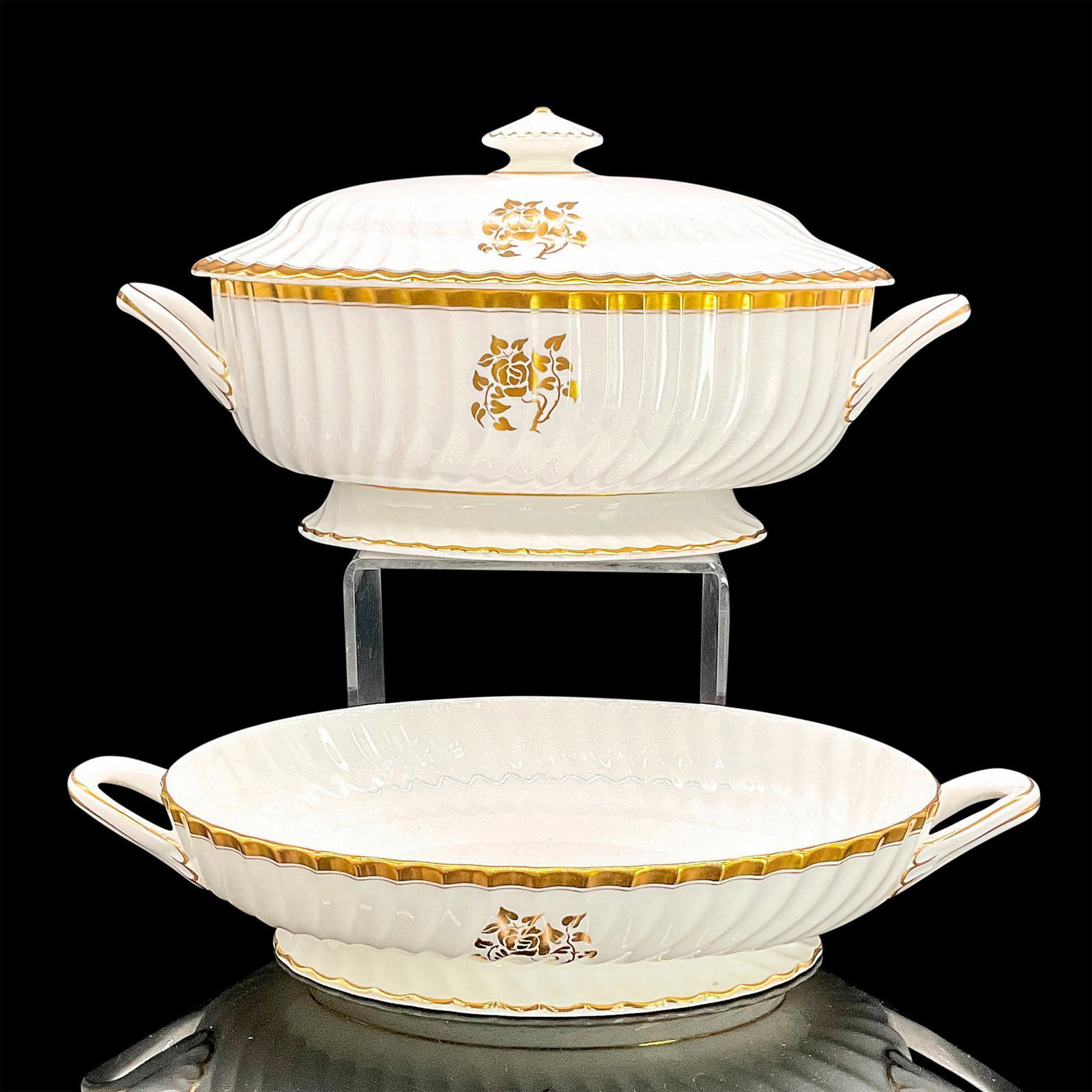 2pc Minton Bone China Serving Dishes, Gold Rose: Two oval white serving dishes with handles, gold flower and leaf decoration and accents. Minton backstamp. The taller with lid is 13.5"L x 7"W x 7"H. The shorter dish is 13.5"L x 7"W x 2"H. The lid fi