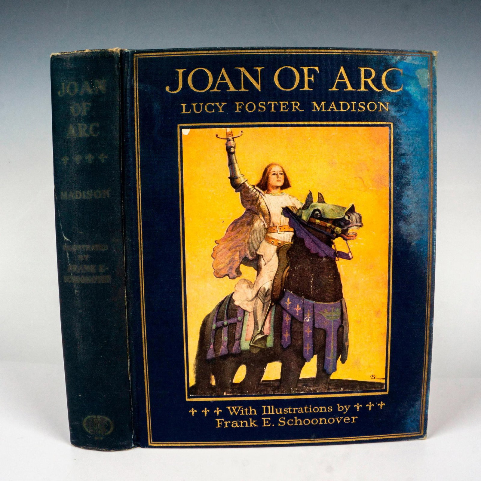 Joan of Arc, Book by Lucy Foster Madison: Blue cloth on boards with bright, full size/full color portrait of Joan of Arc pasted on plate to cover. Gilt lettering and double lined stamped gilt border around outer edge and around plate to front