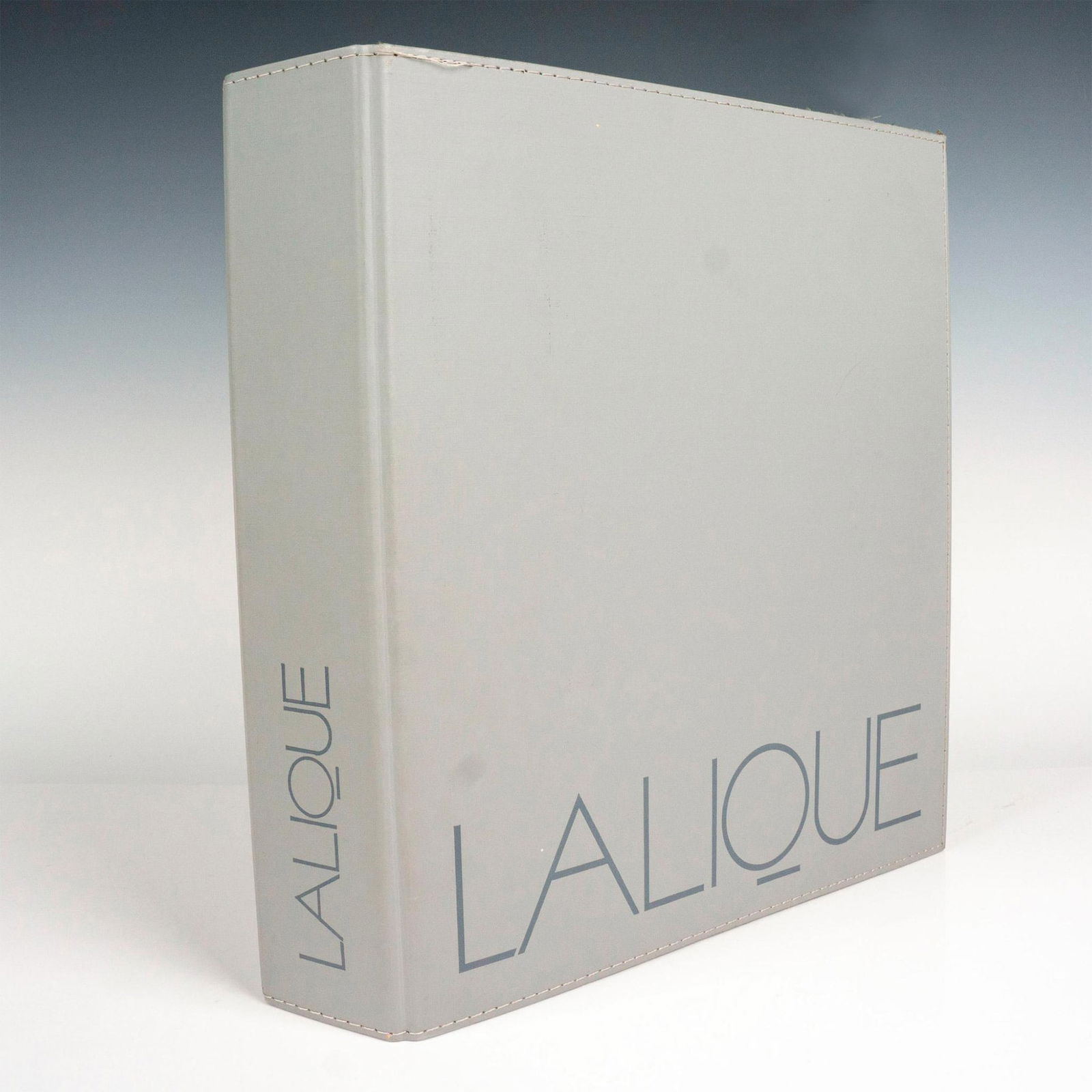 Lalique French/English Reference Catalogue Binder: Large Lalique reference catalogue binder organized in alphabetical order. It includes full color photographs of decorative objects, jewelries, glassware, vases, and luxury items sold in store. Include