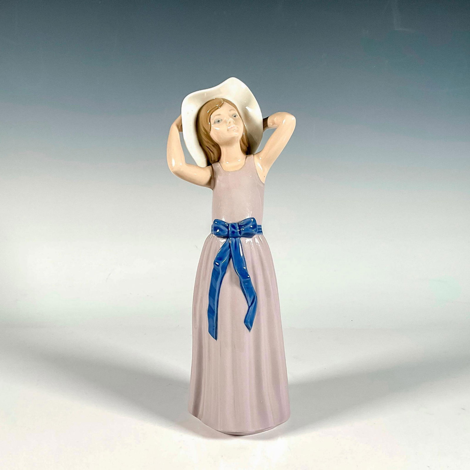 Coy 1005011 - Lladro Porcelain Figurine: Glossy finish; Lladro backstamp. Includes original box. Box measures: 13.5"L x 5"W x 5"H. Artist: Francisco Catala Issued: 1978 - 1998 Dimensions: 10.25"H x 4"W Manufacturer: Lladro Country of Origin: