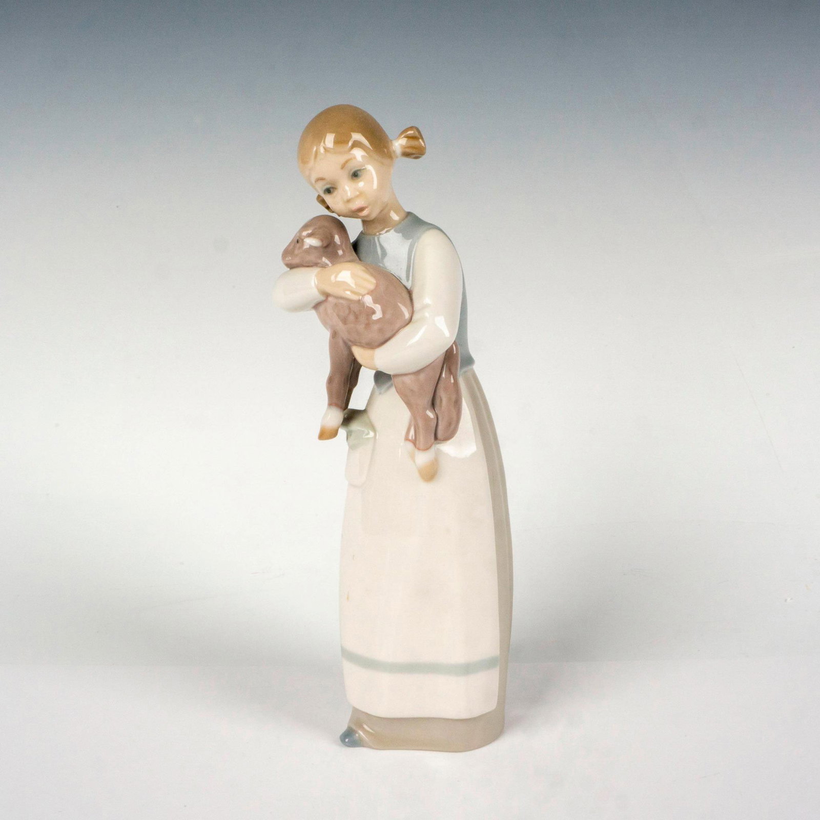 Girl With Lamb 1001010 - Lladro Porcelain Figurine: Glossy finish; Lladro backstamp. Artist: Julio Fernandez Issued: 1969-1993 Dimensions: 2.75"L x 2.5"W x 8.5"H Manufacturer: Lladro Country of Origin: Spain