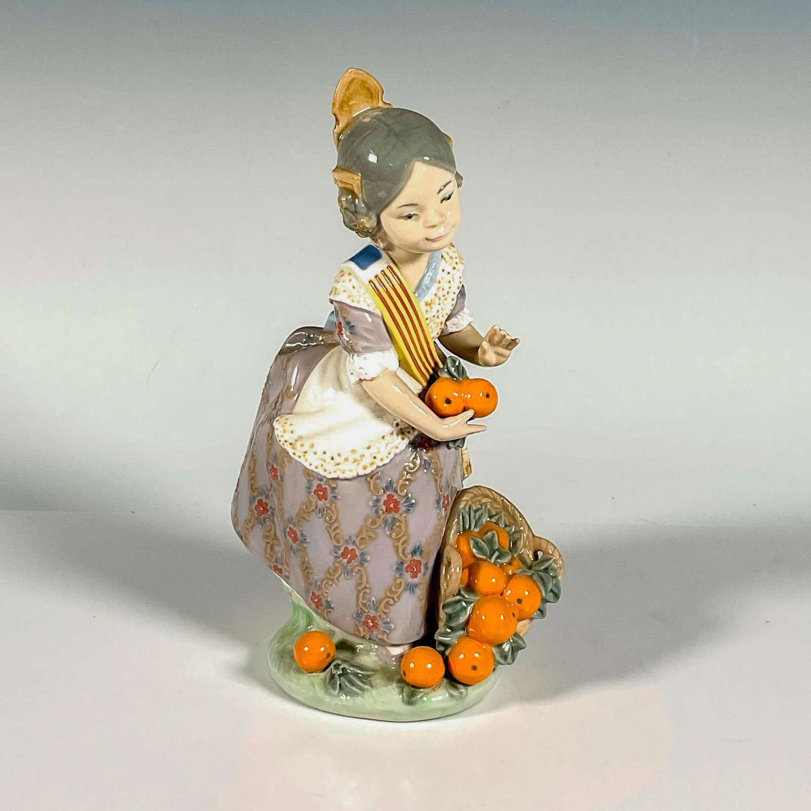 Miss Valencia 1001422 - Lladro Porcelain Figurine: Glossy finish; Lladro backstamp. Includes original box. Box measures: 11"L x 5.75"W x 5"H. Artist: Juan Huerta Issued: 1982 - 1997 Dimensions: 7.5"H Manufacturer: Lladro Country of Origin: Spain