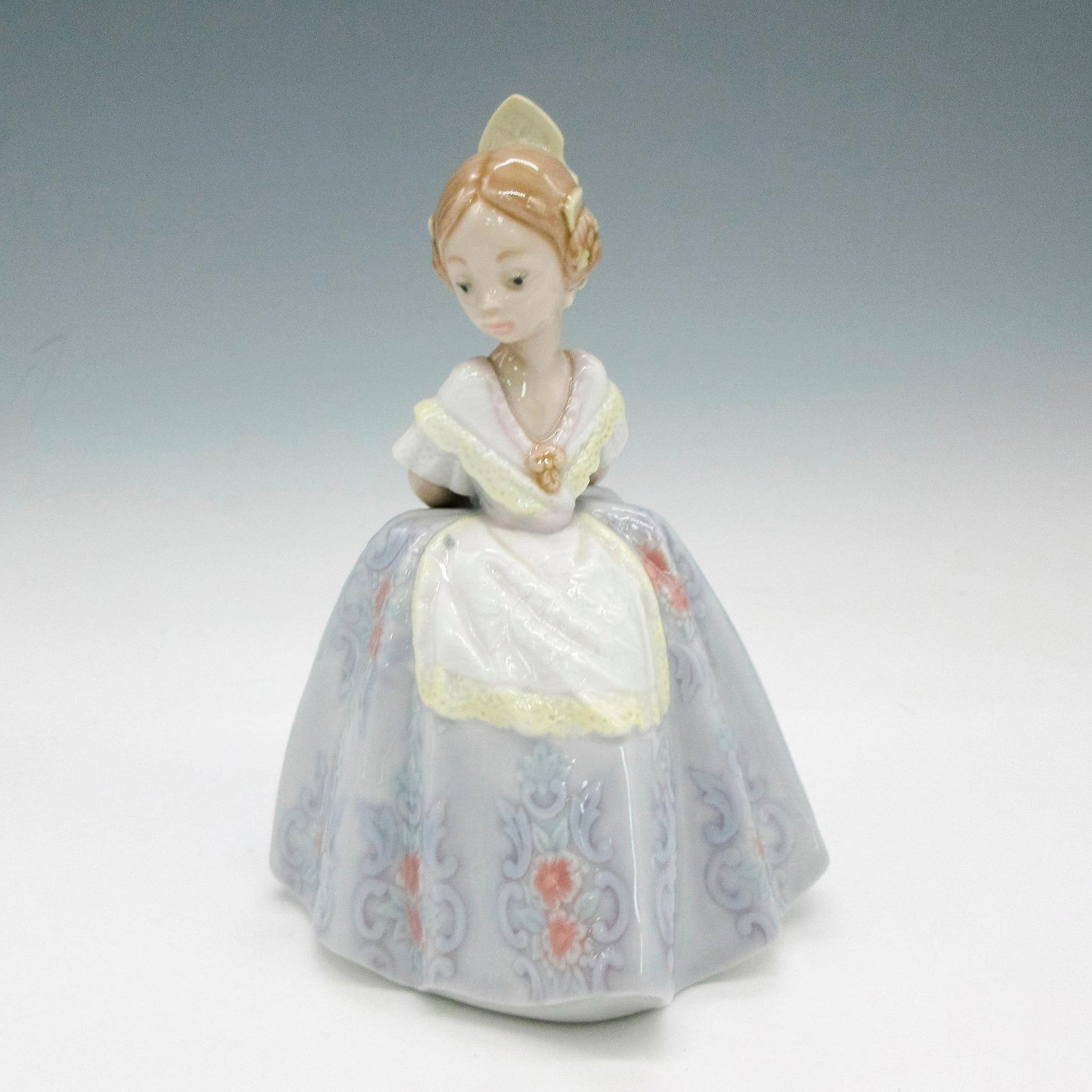 Pepita 1005374 - Lladro Porcelain Figurine: Glazed figural dressed in traditional dress colored in soft blue, red and yellow. Lladro backstamp. Issued: 1986 - 1993 Dimensions: 3.75"L x 3.5"W x 5.5"H Manufacturer: Lladro Country of Origin: Spain