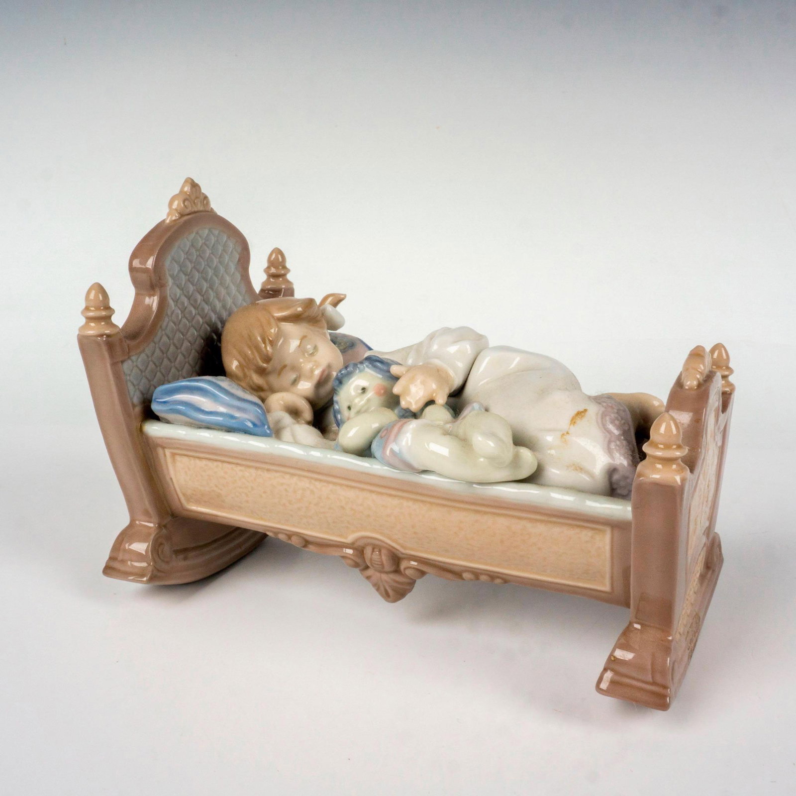 Rock A Bye Baby 1005717 - Lladro Porcelain Figurine: Glossy finish; Lladro backstamp. Artist: Francisco Polope Issued: 1990-1999 Dimensions: 3.5"L x 6.5"W x 5"H Manufacturer: Lladro Country of Origin: Spain