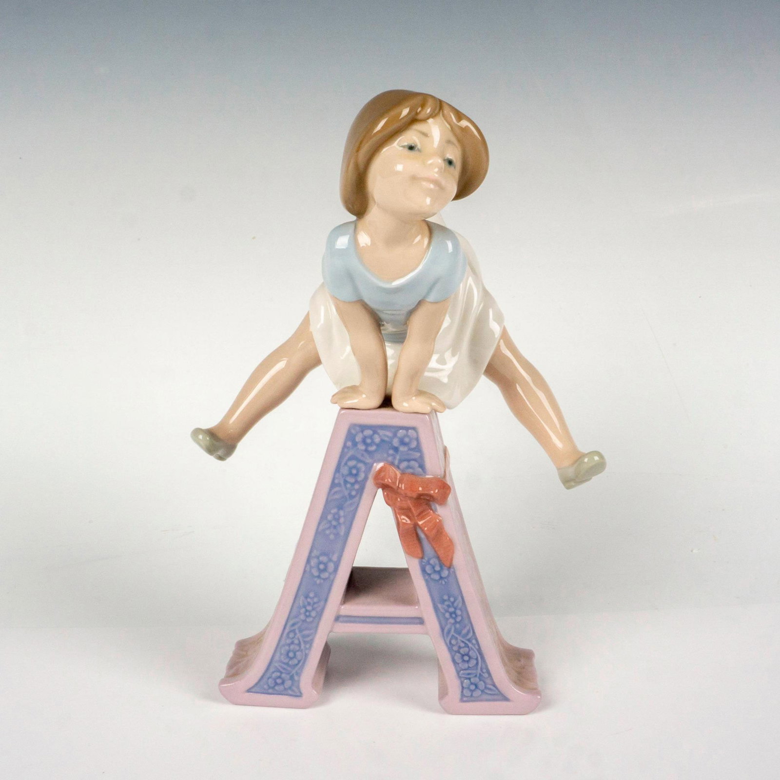 Schoolgirl A 1005145 - Lladro Porcelain Figurine: Glossy finish; Lladro backstamp. Artist: Jose Puche Issued: 1982-1985 Dimensions: 5.75"L x 5"W x 9.5 Manufacturer: Lladro Country of Origin: Spain