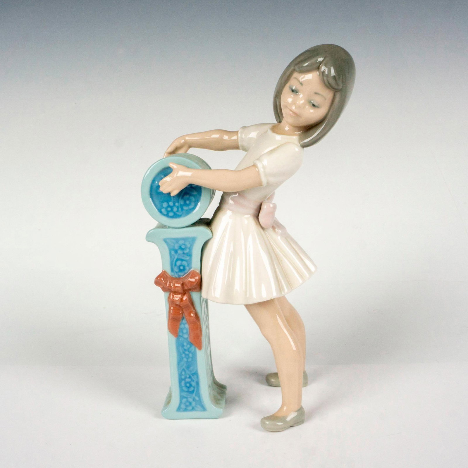Schoolgirl I 1005147 - Lladro Porcelain Figurine: Glossy finish; Lladro backstamp. Artist: Jose Puche Issued: 1982-1985 Dimensions: 4.25"L x 2.75"W x 8"H Manufacturer: Lladro Country of Origin: Spain