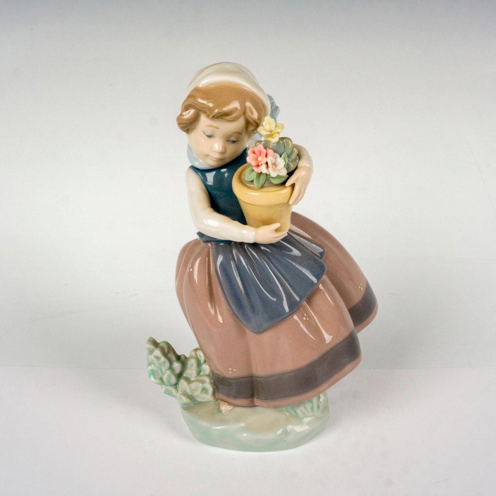 Spring Is Here 1005223 - Lladro Porcelain Figurine: Glossy finish; Lladro backstamp. Artist: Jose Puche Issued: 1984-2021 Dimensions: 4"L x 3.25"W x 6.75"H Manufacturer: Lladro Country of Origin: Spain