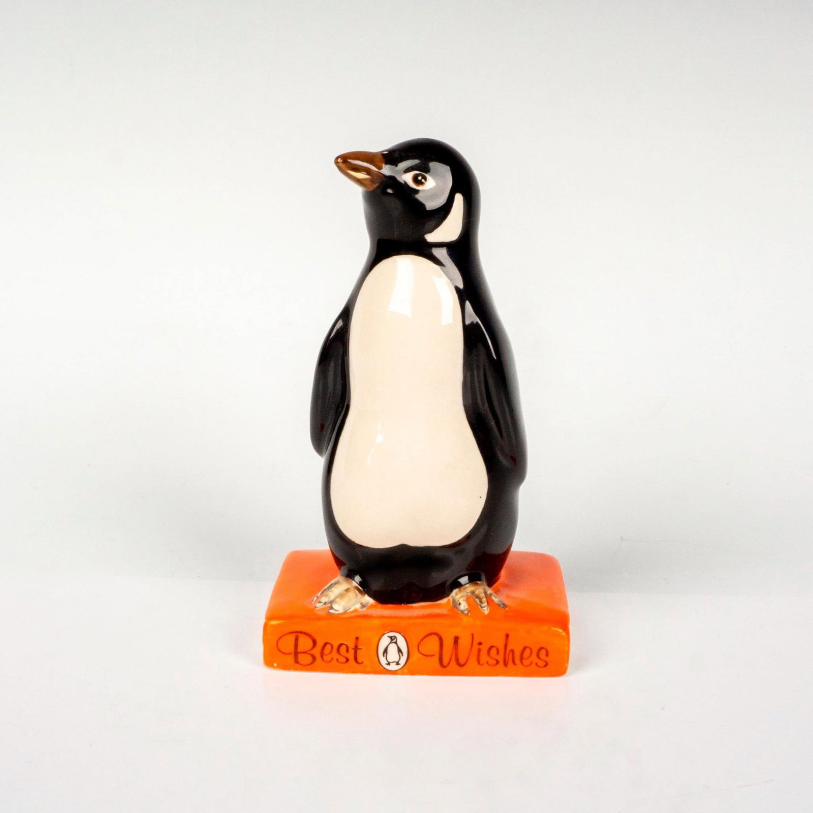 Best Wishes - Royal Doulton Advertising Figurine: Glossy porcelain, commissioned advertising for the British Publishing House Penguin Books. Royal Doulton backstamp. Issued: c. 1985 Dimensions: 2.75"L x 1.75"W x 4.5"H Manufacturer: Royal Doulton Coun