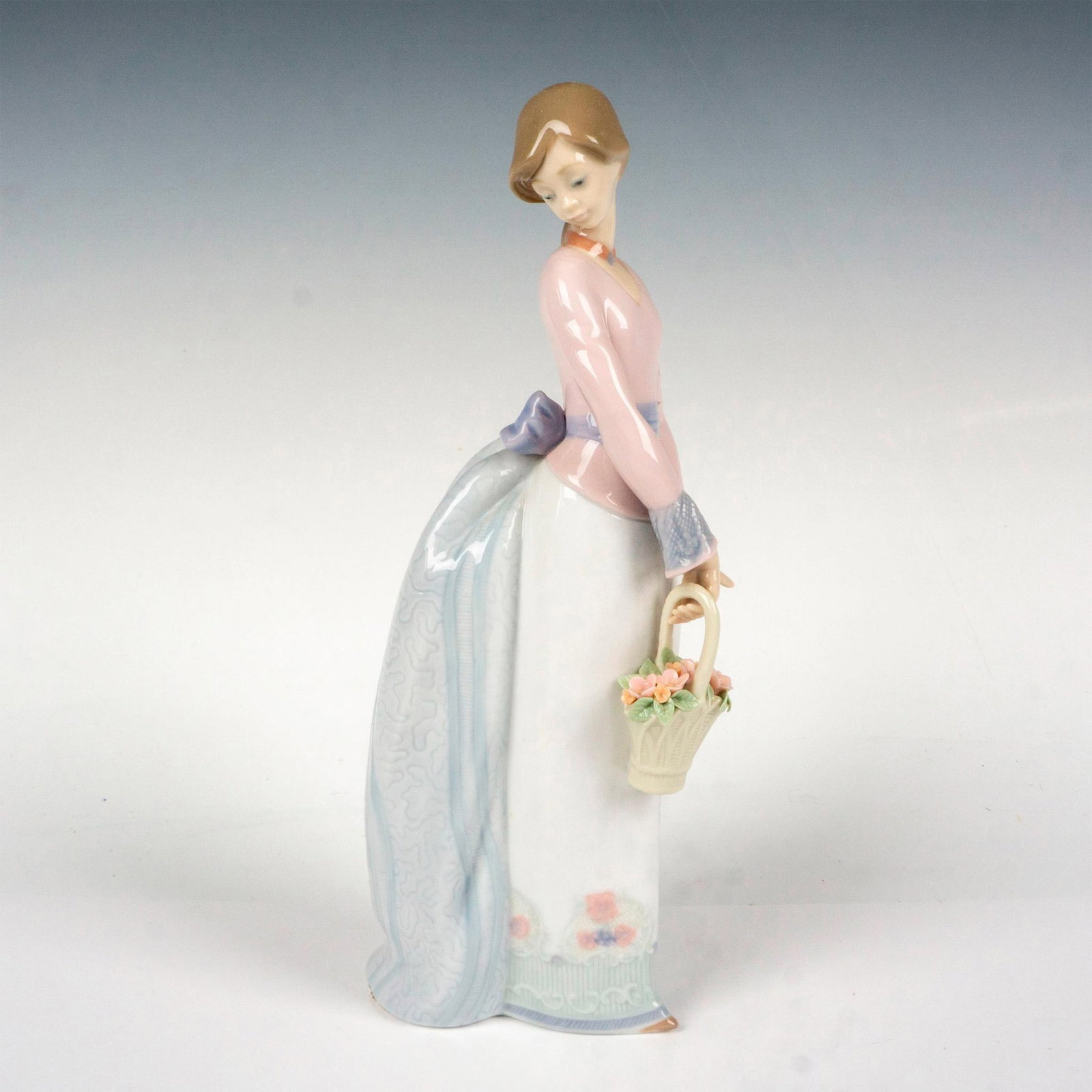 Basket Of Love 1007622 - Lladro Porcelain Figurine: Glossy finish; Lladro backstamp. Artist: Jose Puche Issued: 1994 - 1994 Dimensions: 9.75"H x 4"W Manufacturer: Lladro Country of Origin: Spain