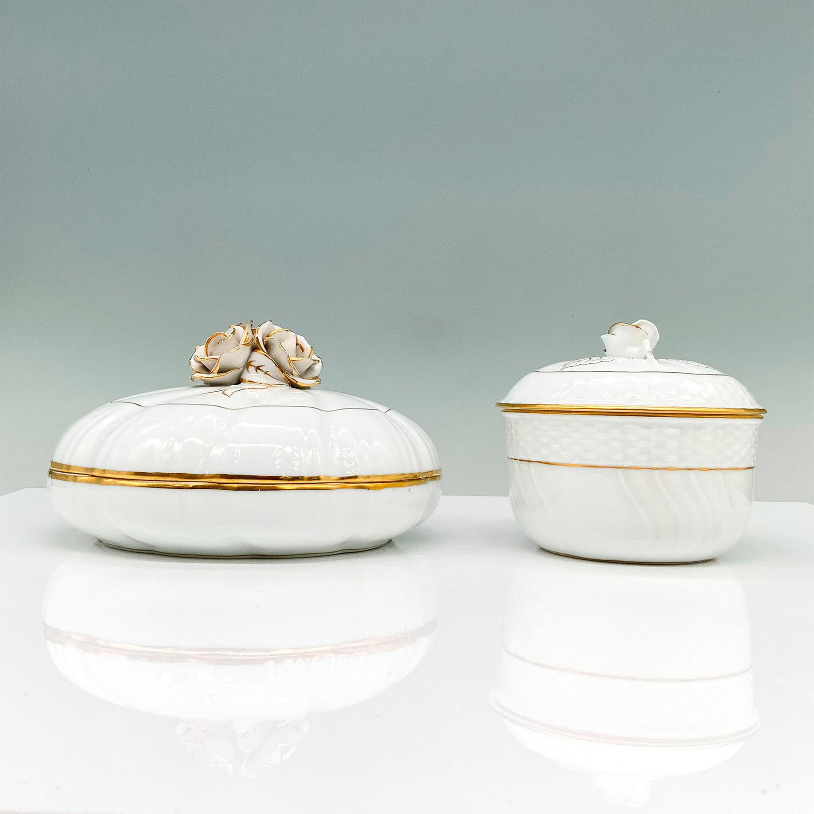Pair of Herend Porcelain Rose Lidded Bowls: White lidded sugar and serving bowls decorated with finial roses on lids and gold trim throughout. Herend backstamp. Dimensions of the largest item: 6.5"L x 6.5"W x 4.5"H. Manufacturer: Herend Country