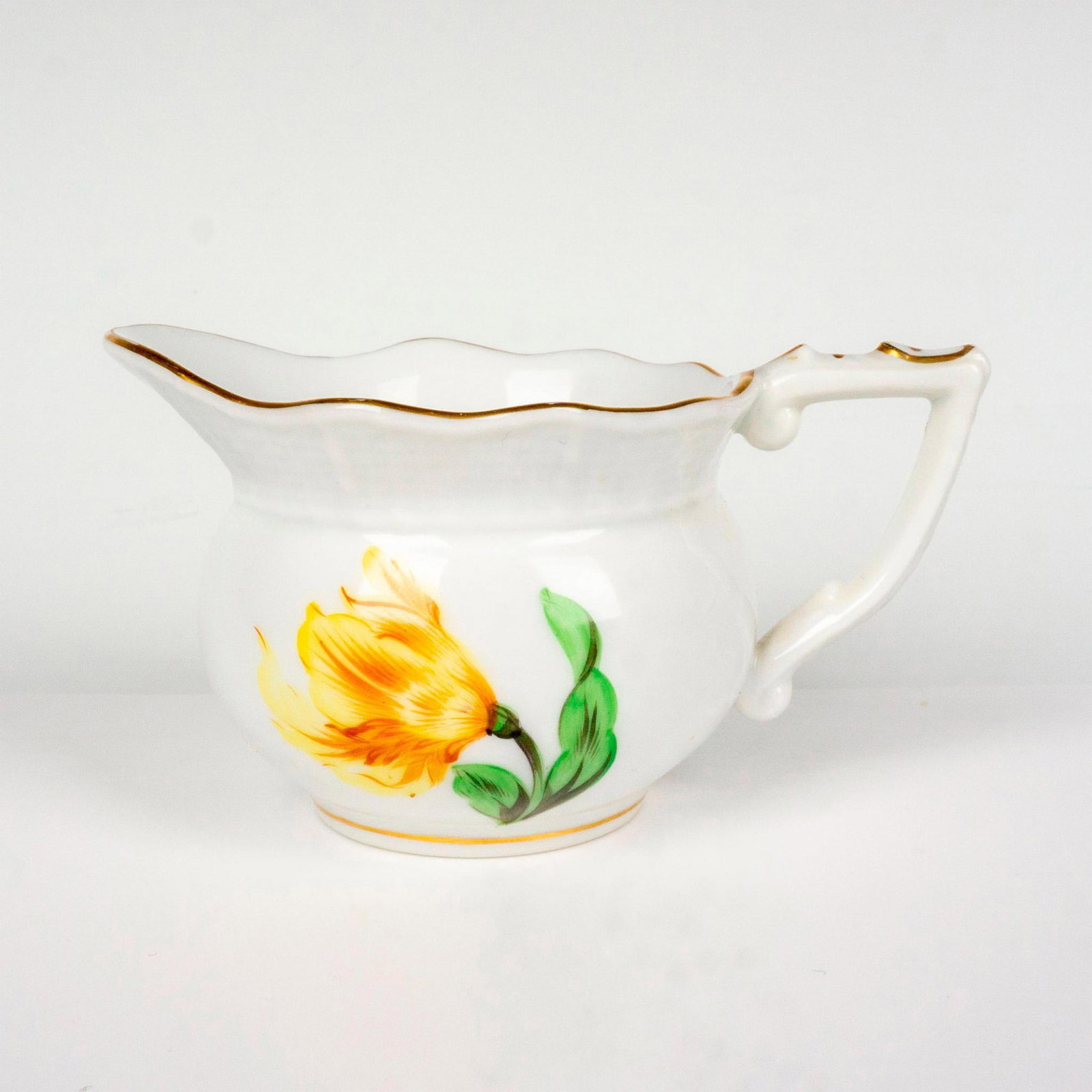 Herend Porcelain Floral Creamer: Hand painted creamer decorated with a large yellow flower, surrounded by mini colorful flowers. Gilded accents with scalloped border. Herend backstamp. Issued: 20th c. Dimensions: 3.75"L x 2.25"W x 2"
