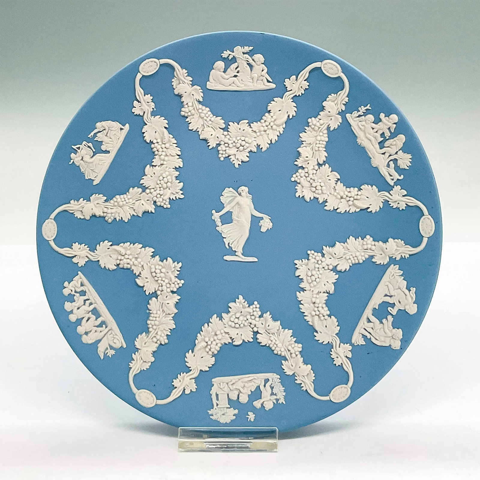 Wedgwood Jasperware Collectors Society Plate: Matte blue stoneware with white neoclassical sprigged decoration of various people, grapes and leaves in low-relief. Wedgwood backstamp. Dimensions: 0.75"H x 6.5"dia Manufacturer: Wedgwood Country of 