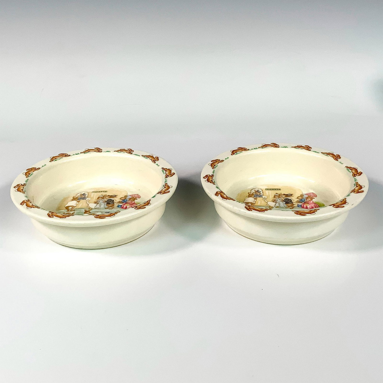Pair of Royal Doulton Bunnykins Childrens Bowls: A lovely set of cereal bowls featuring a Bunnykins family scene in center with running bunny border. Royal Doulton Bunnykins backstamp. Dimensions: 6.25"W x 1.75"H Manufacturer: Royal Doulton Country 