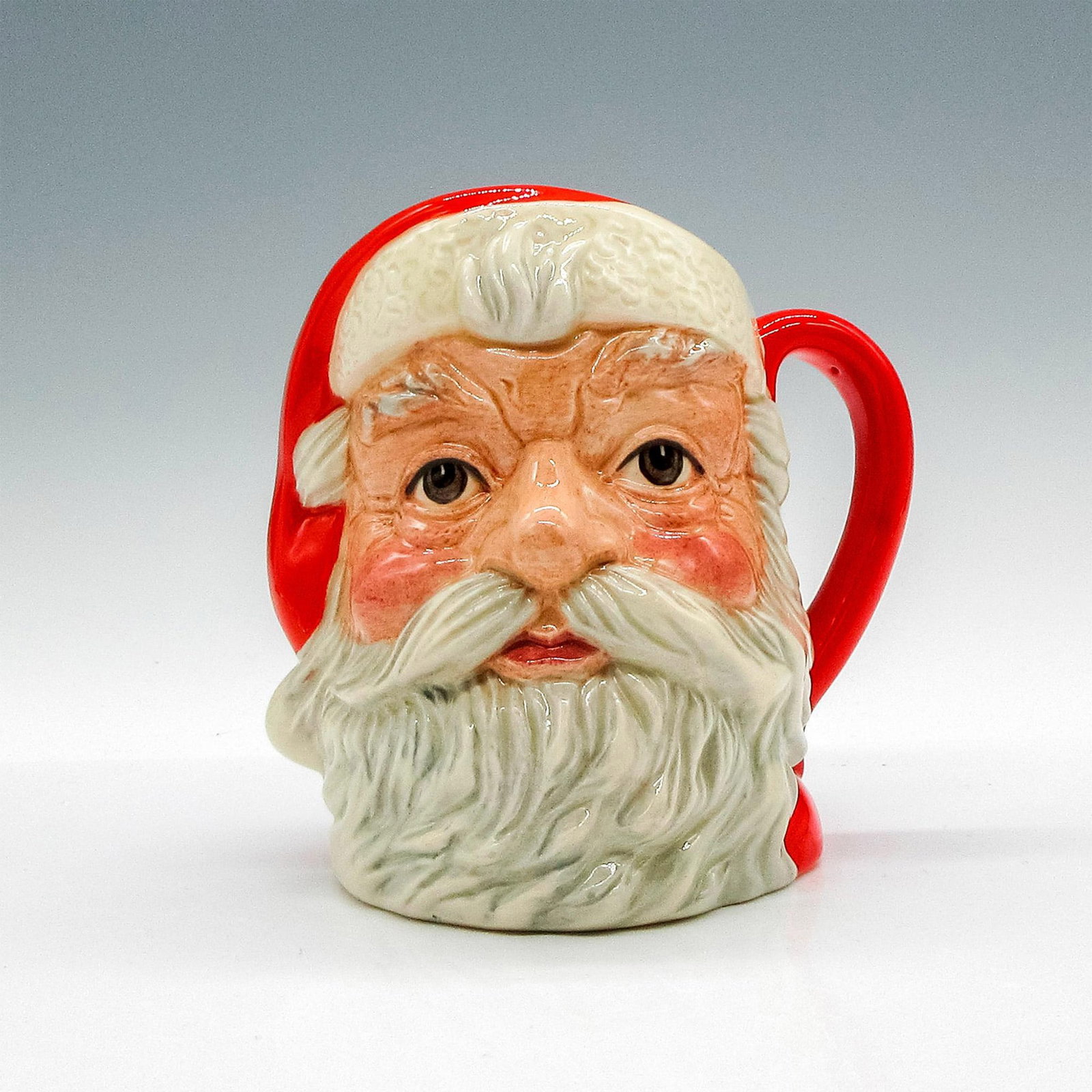 Santa Claus (Plain Handle) D6705 - Small - Royal Doulton Character Jug: Style Four, plain red handle. Red and white colorway. The Santa Claus jug was introduced in 1981 and was the first to undergo annual design changes. Featuring different well-known Christmas themes, th