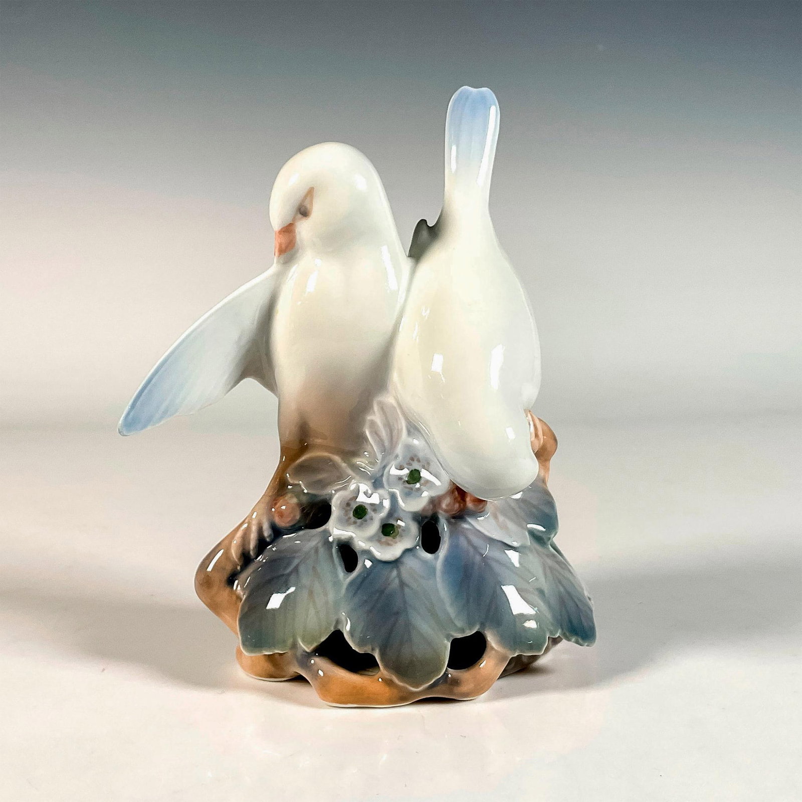 Royal Copenhagen Porcelain Figurine, Lovebirds: Features two doves standing atop a floral adorned, reticulated base. Finished in an overall glaze; no. 402. Royal Copenhagen backstamp. Artist: Theodor Madsen Issued: 20th c. Dimensions: 4.25"L x 2.5"