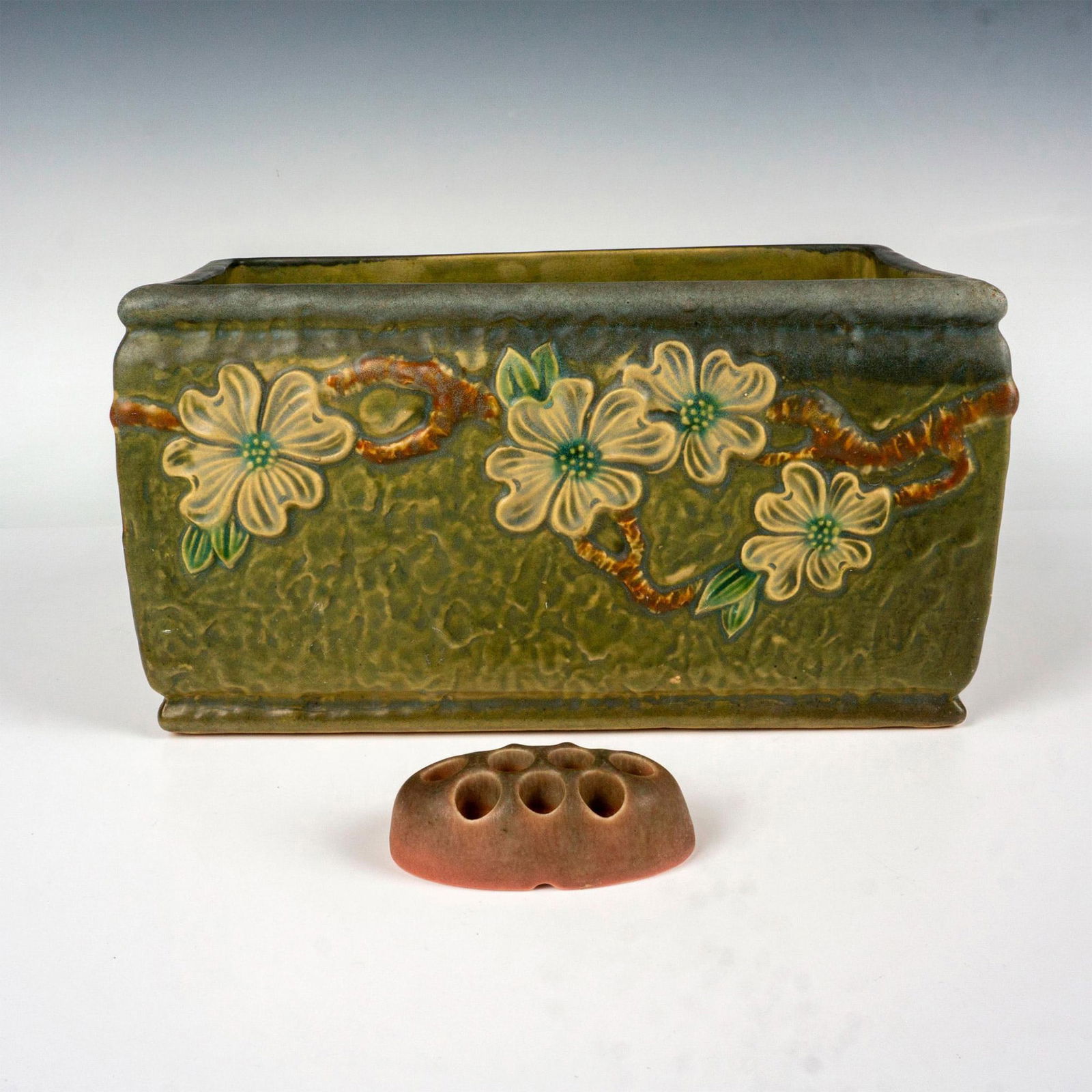 2pc Roseville Pottery Planter and Rookwood Flower Frog: This pair includes Roseville pottery planter in the dogwood pattern stamped with the blue R to base and a Rookwood flower frog stamped 2612A to base. Larger piece measures: 12"L x 6"W x 6.5"H. Issued: