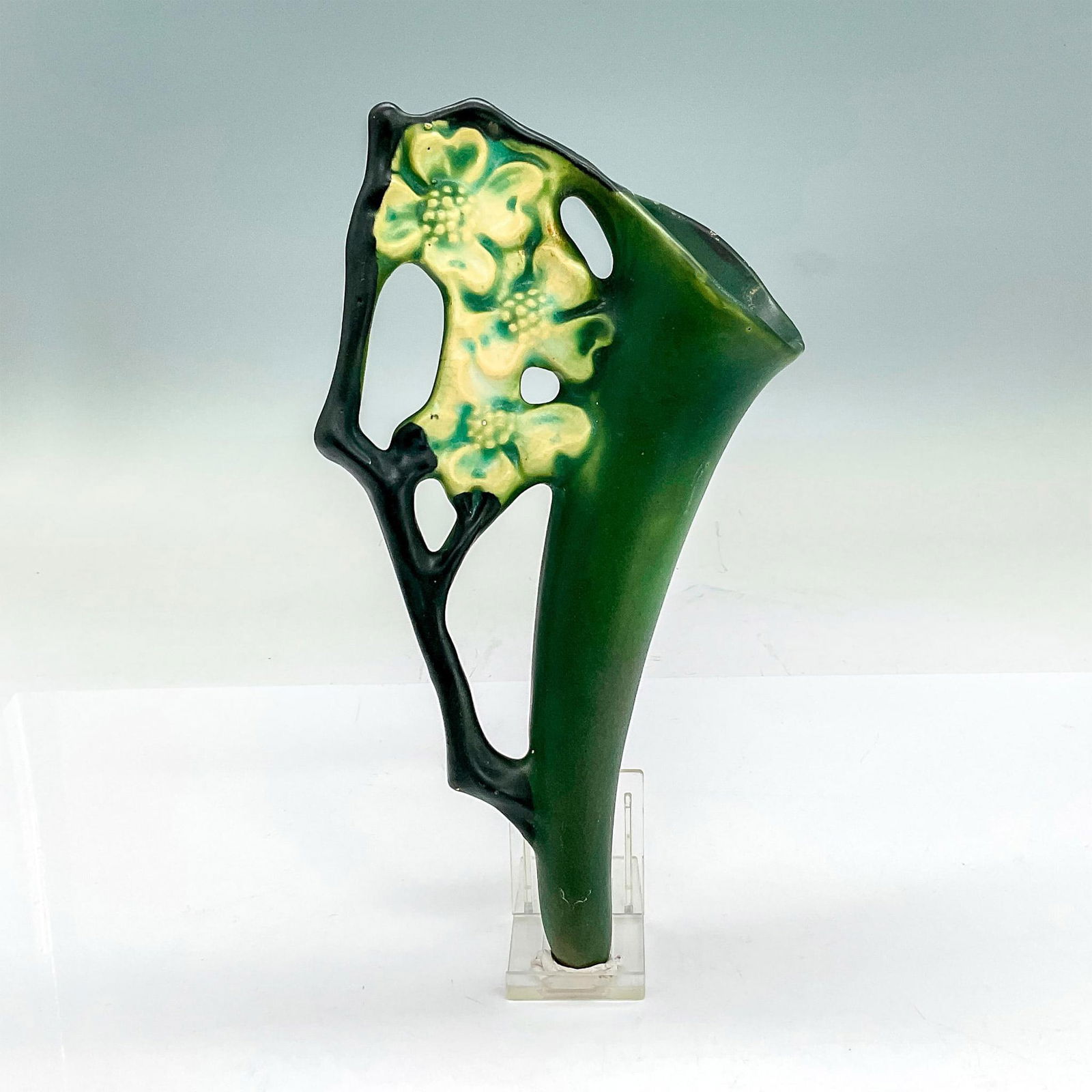 Roseville Pottery Wall Pocket, Dogwood: Earthenware wall vase in a pattern that features flowering dogwood branches of white flowers on a dark green background with a black side handle. Issued: circa 1920 Dimensions: 9.75"H x 5.5"W x 2.5"D