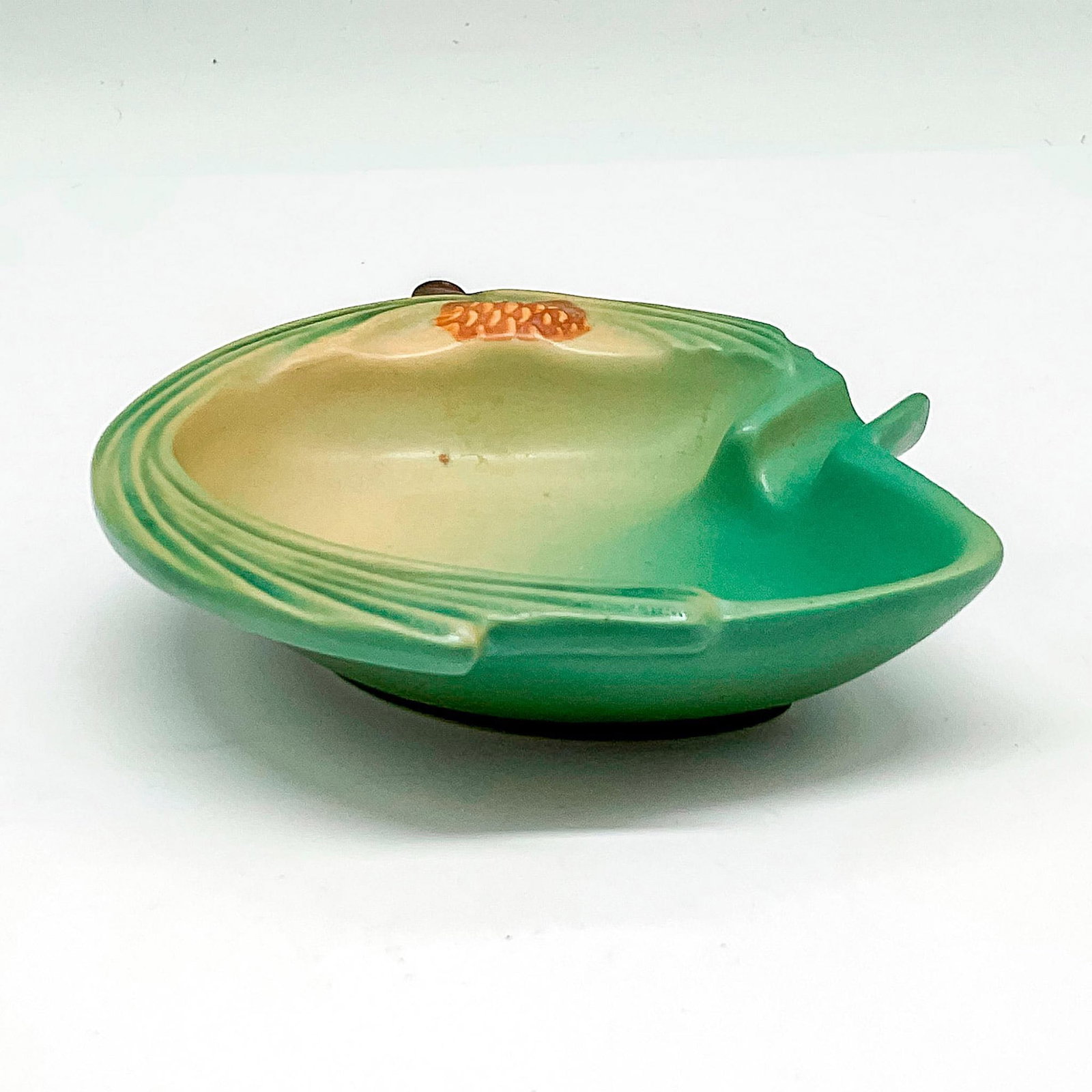 Roseville Pottery Ashtray, Pinecone Green: Matte finish over sage green with pinecone design colored in brown. Roseville USA raised mark. 499. Issued: 20th century Dimensions: 4.25"L x 4.25"W x 1.25"H Manufacturer: Roseville Country of Origin: