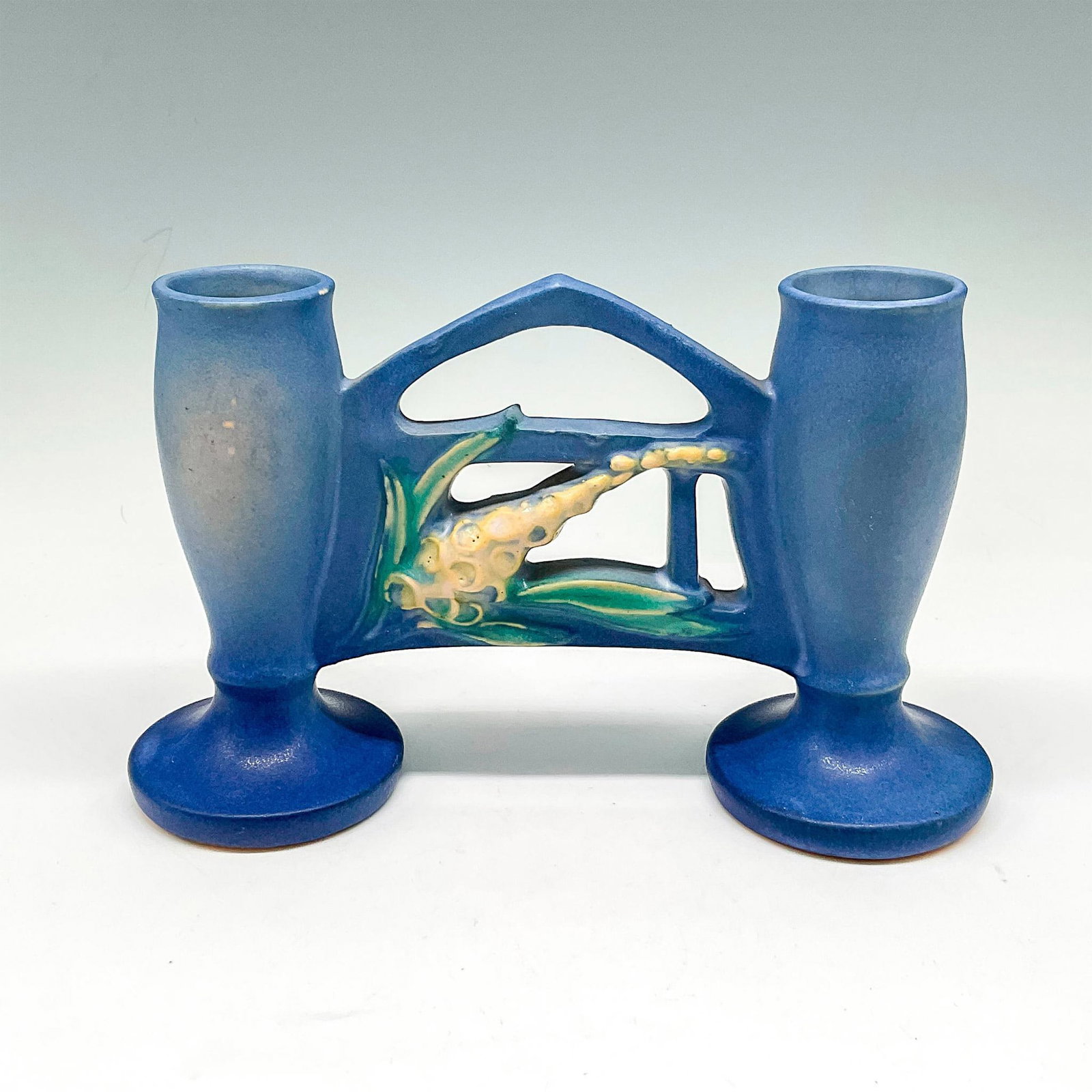 Roseville Pottery Double Gate Vase, Foxglove Blue: Light glaze over base berry color with floral design on gate. Roseville USA raised mark. 160. Issued: 20th century Dimensions: 7.5"L x 2.5"W x 5"H Manufacturer: Roseville Country of Origin: United Sta