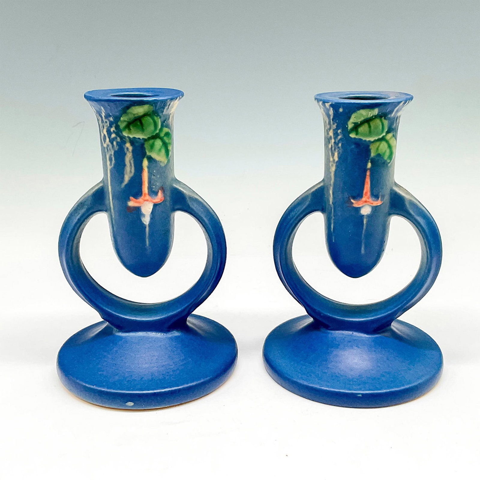 2pc Roseville Pottery Candle Holders, Fuchsia Blue: Matte finished suspended holders colored in blue with floral and vine design at top. Roseville impressed mark. 1133. Manufacturer: Roseville Country of Origin: United States