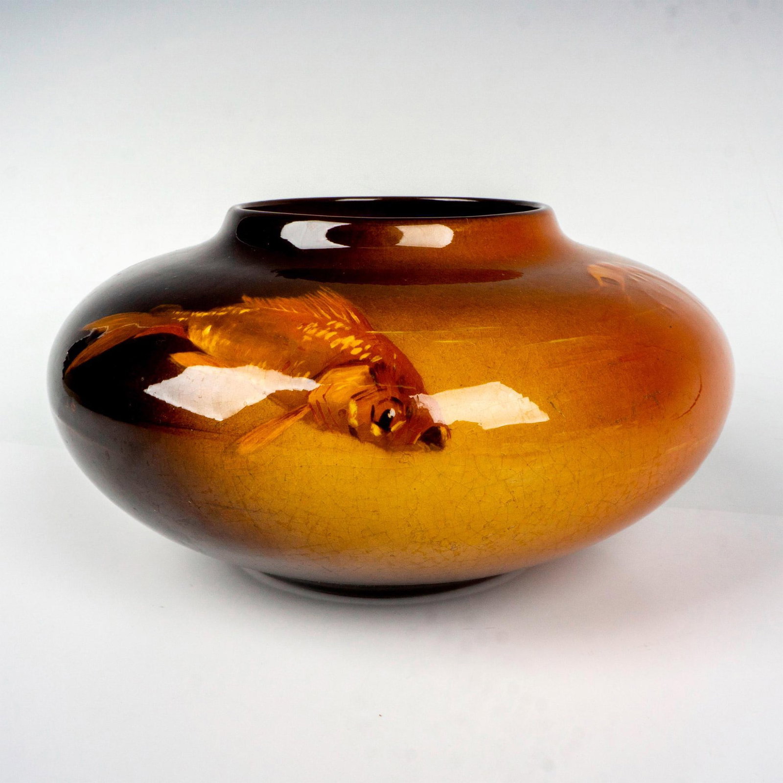 J. B. Owens Pottery Utopian Vase: Pulchritudinous vessel of squat form decorated with swimming fish on a brown glazed ground. J. B. Owen Utopian impressed backstamp. Dimensions: 7.5"W x 4"H Manufacturer: Owens Pottery Country of Origi