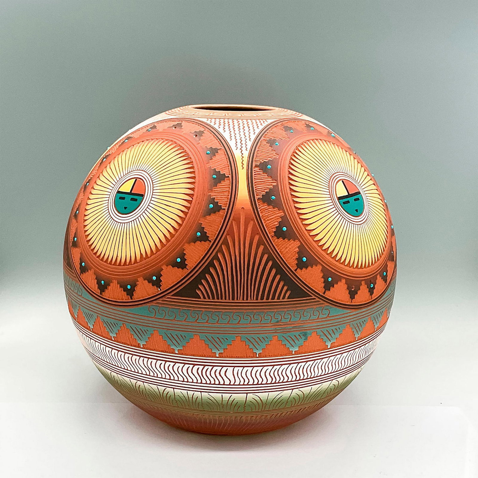 Terracotta Orb Pot by Navajo Artist Lori Smith: Stunning detailed etched round pot in Earth tones of orange, brown, yellow, green, white and turquoise featuring the Navajo Sun Face. Artist signed L Smith Navajo to bottom. Lori's process begins with